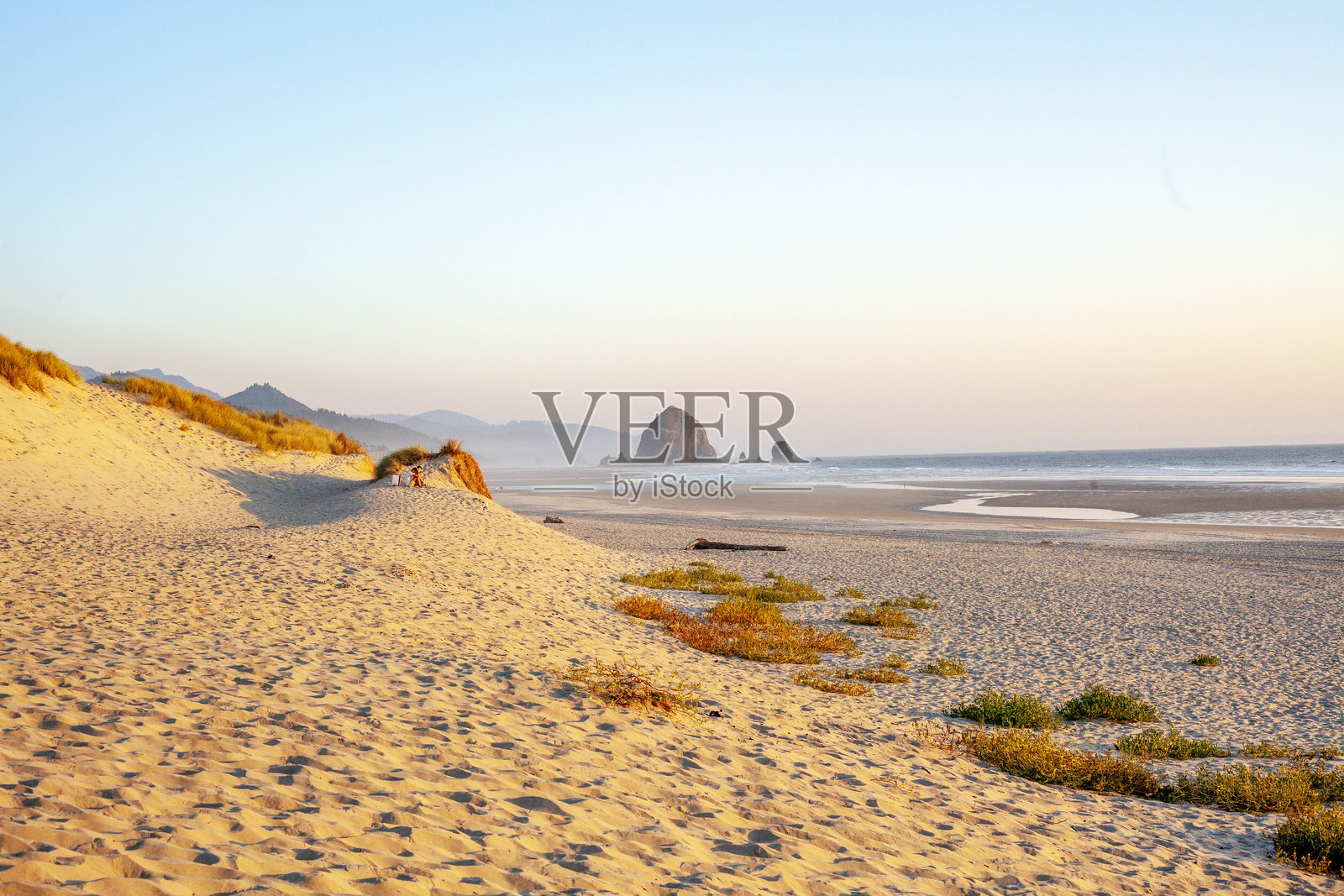 日落时分，沙滩上眺望海洋中的岛屿照片摄影图片