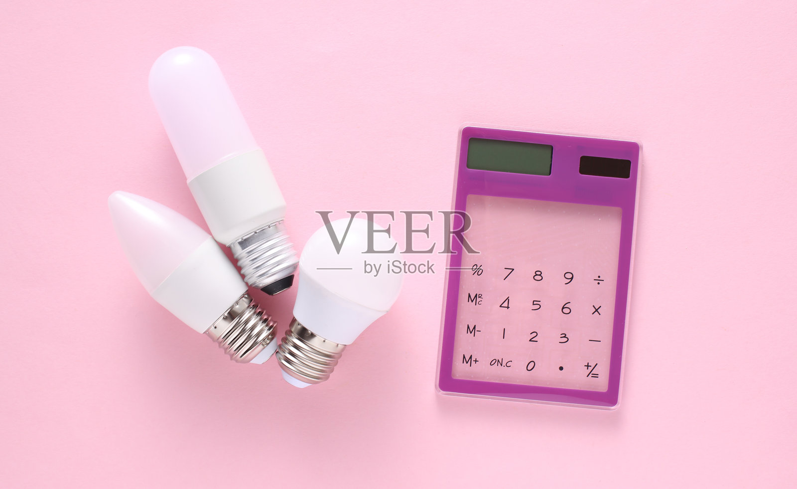 能源效率。粉色背景上的节能LED灯泡计算器照片摄影图片