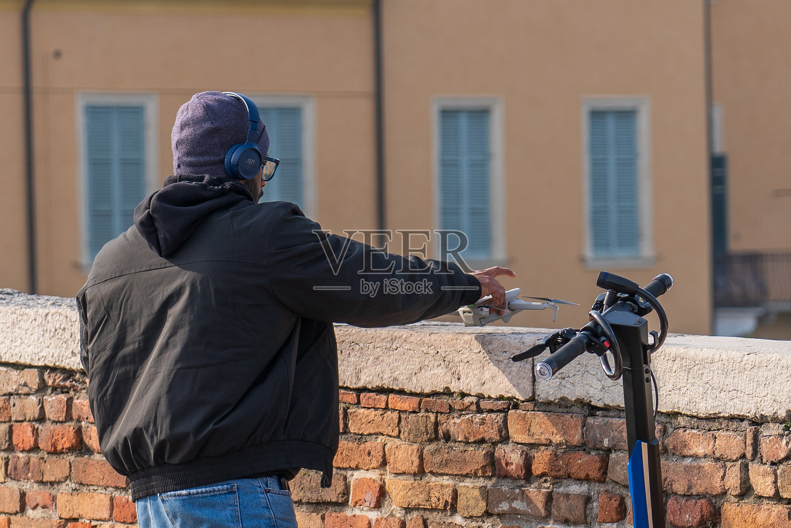 一名戴着耳机的男子正在起飞四旋翼无人机照片摄影图片