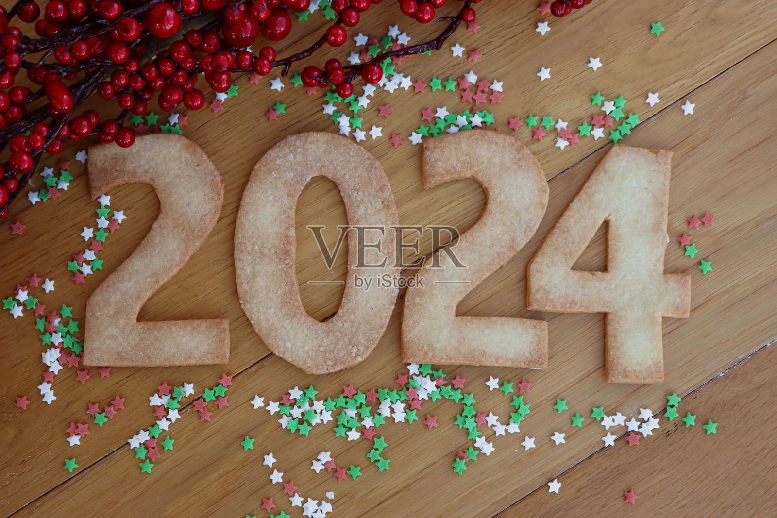 木桌上摆放着数字2024形状的饼干，上面撒着五颜六色的糖屑照片摄影图片