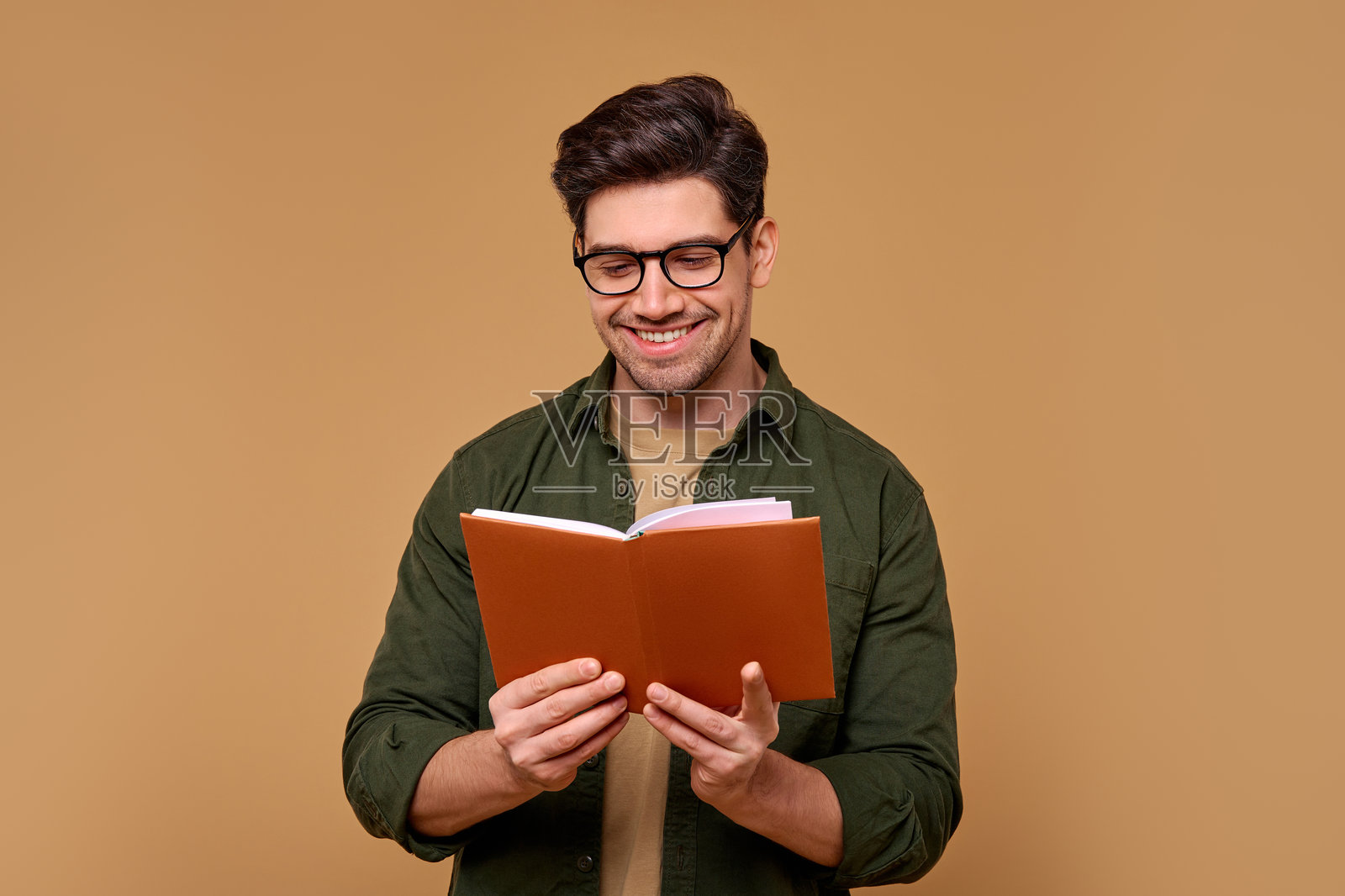 一个快乐微笑的男人在温馨的棕色背景中享受阅读一本书的时光照片摄影图片
