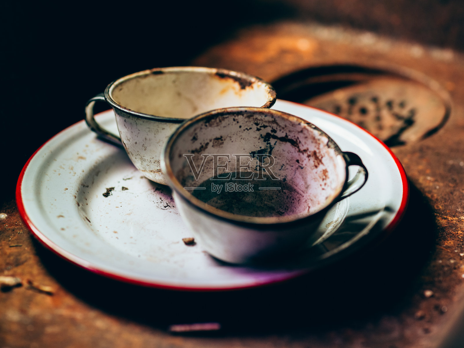 生锈的旧水槽中的古董珐琅盘子照片摄影图片