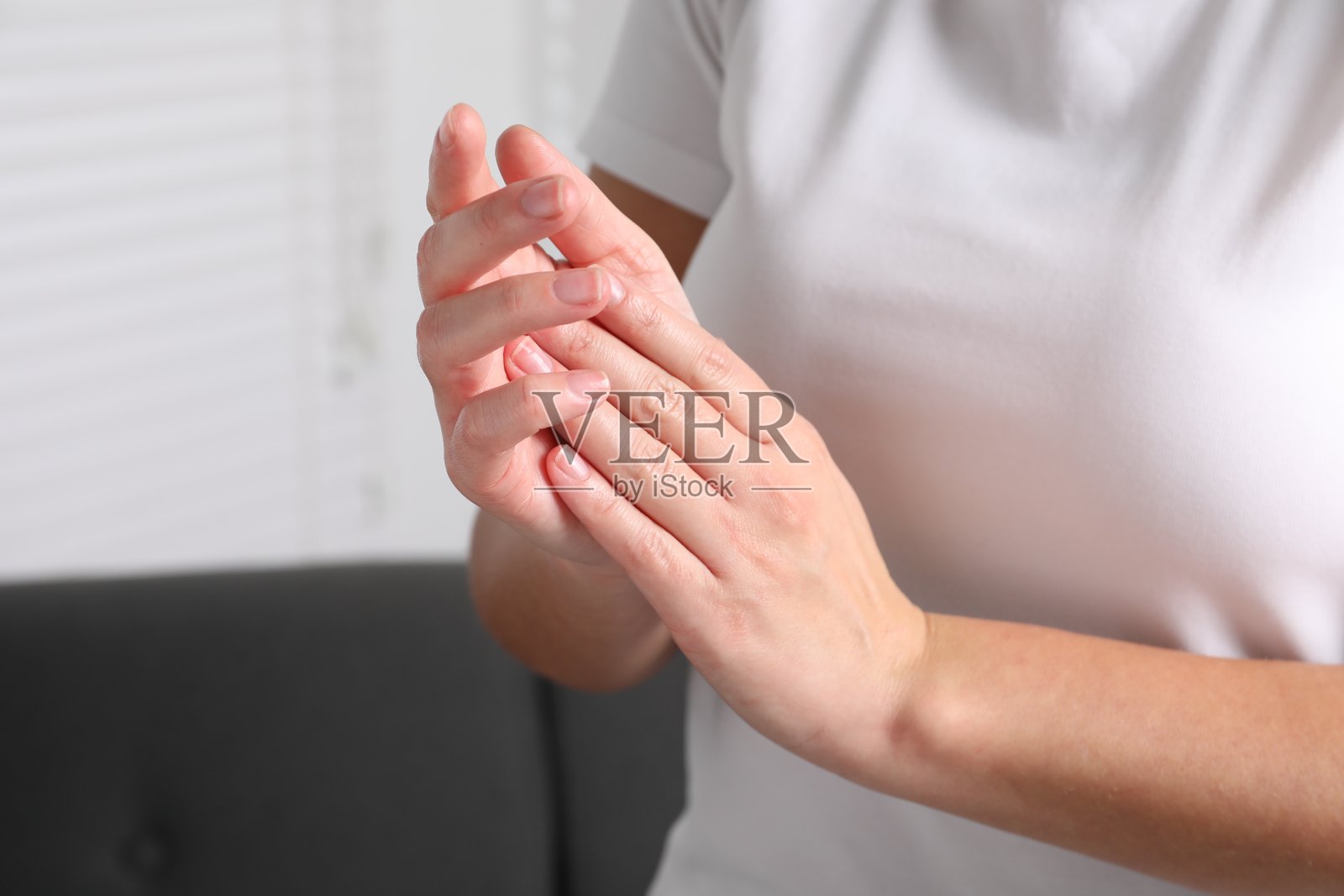 女人在模糊背景下近距离涂抹护肤霜于手部照片摄影图片