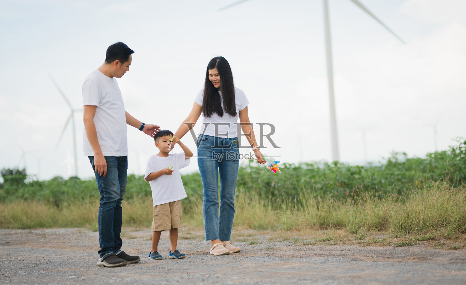 一家三口，男人、女人和一个孩子，站在田野里。照片摄影图片