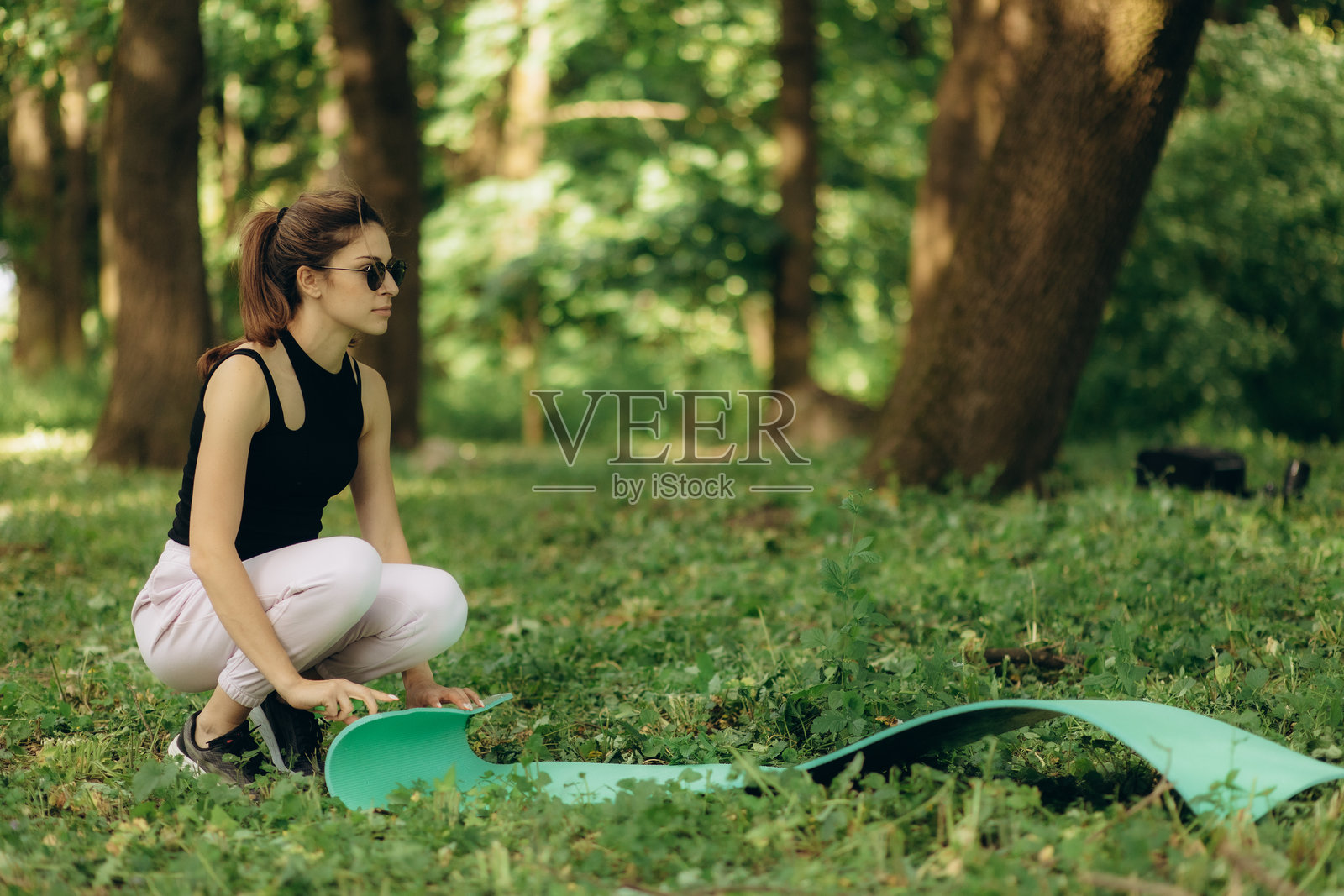 年轻女性在早晨铺开瑜伽垫，准备锻炼。户外瑜伽老师。照片摄影图片