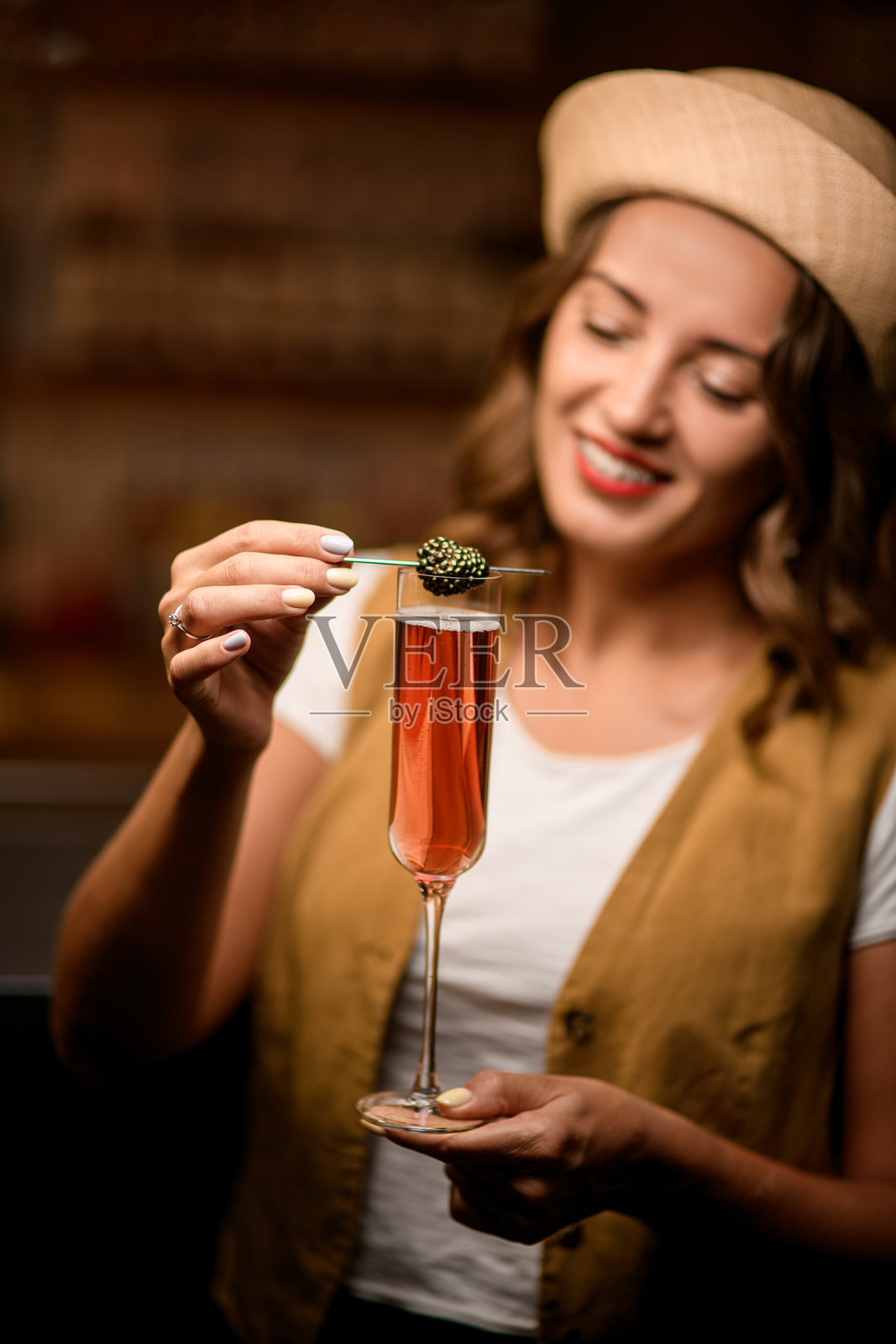 女人一只手拿着装满饮料的高玻璃杯，另一只手拿着黑莓串。照片摄影图片