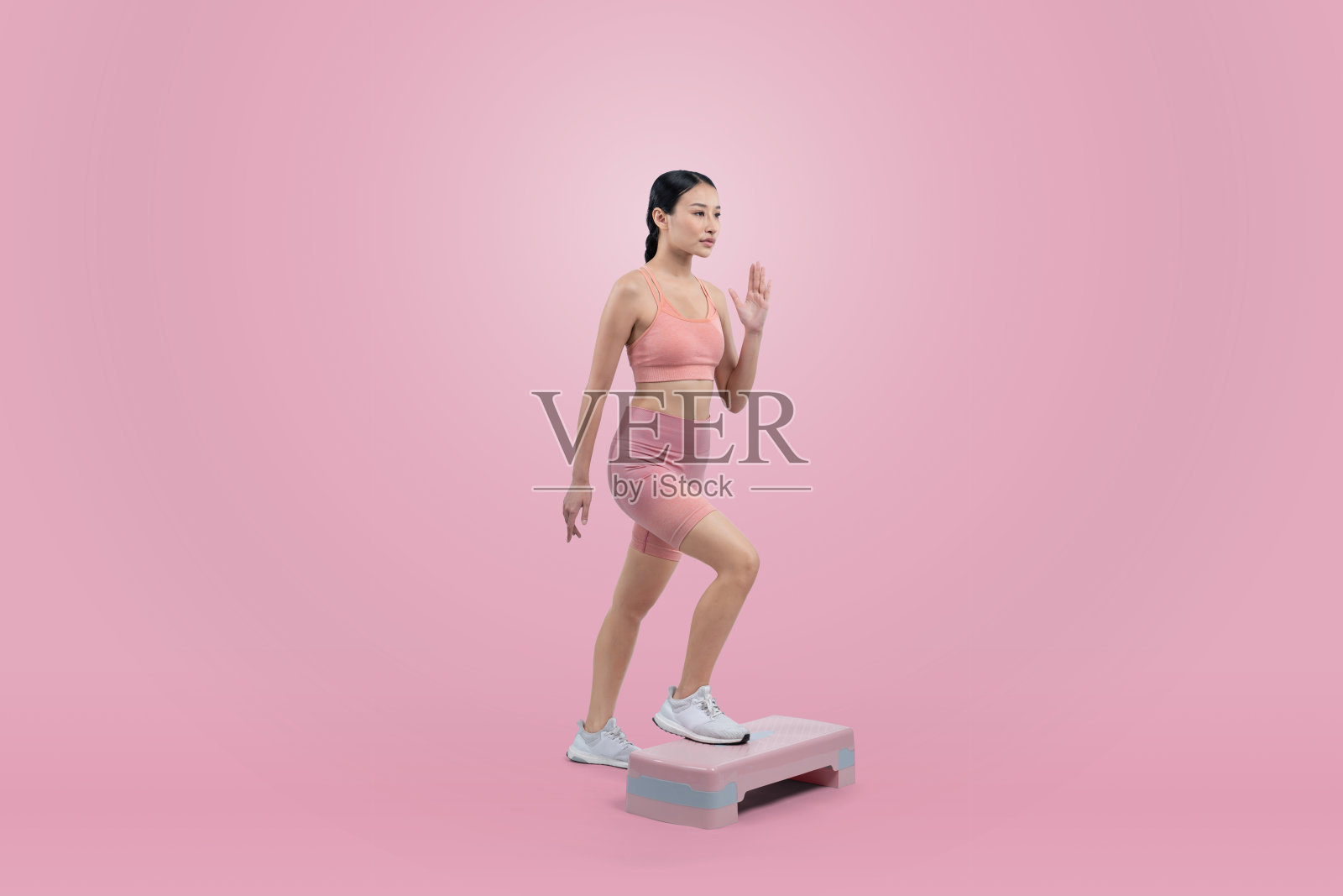 充满活力的女性在工作室进行锻炼，背景简洁明了照片摄影图片