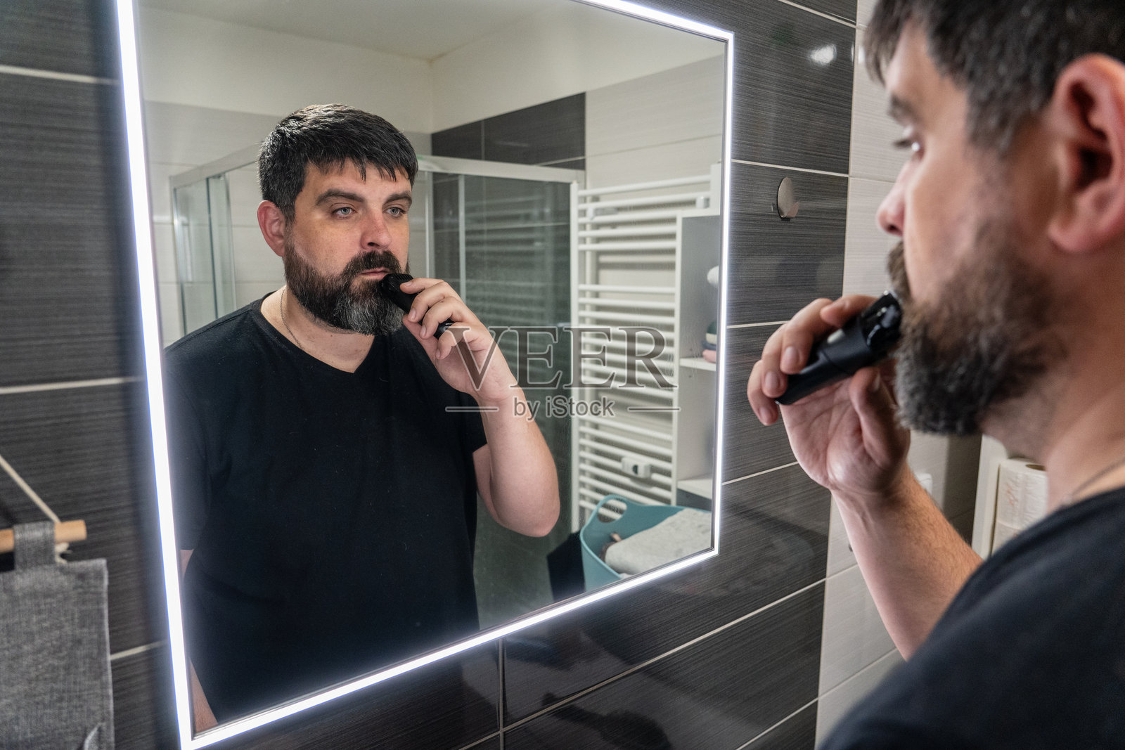 男人在浴室剃胡子。胡须护理，电动剃须刀。照片摄影图片