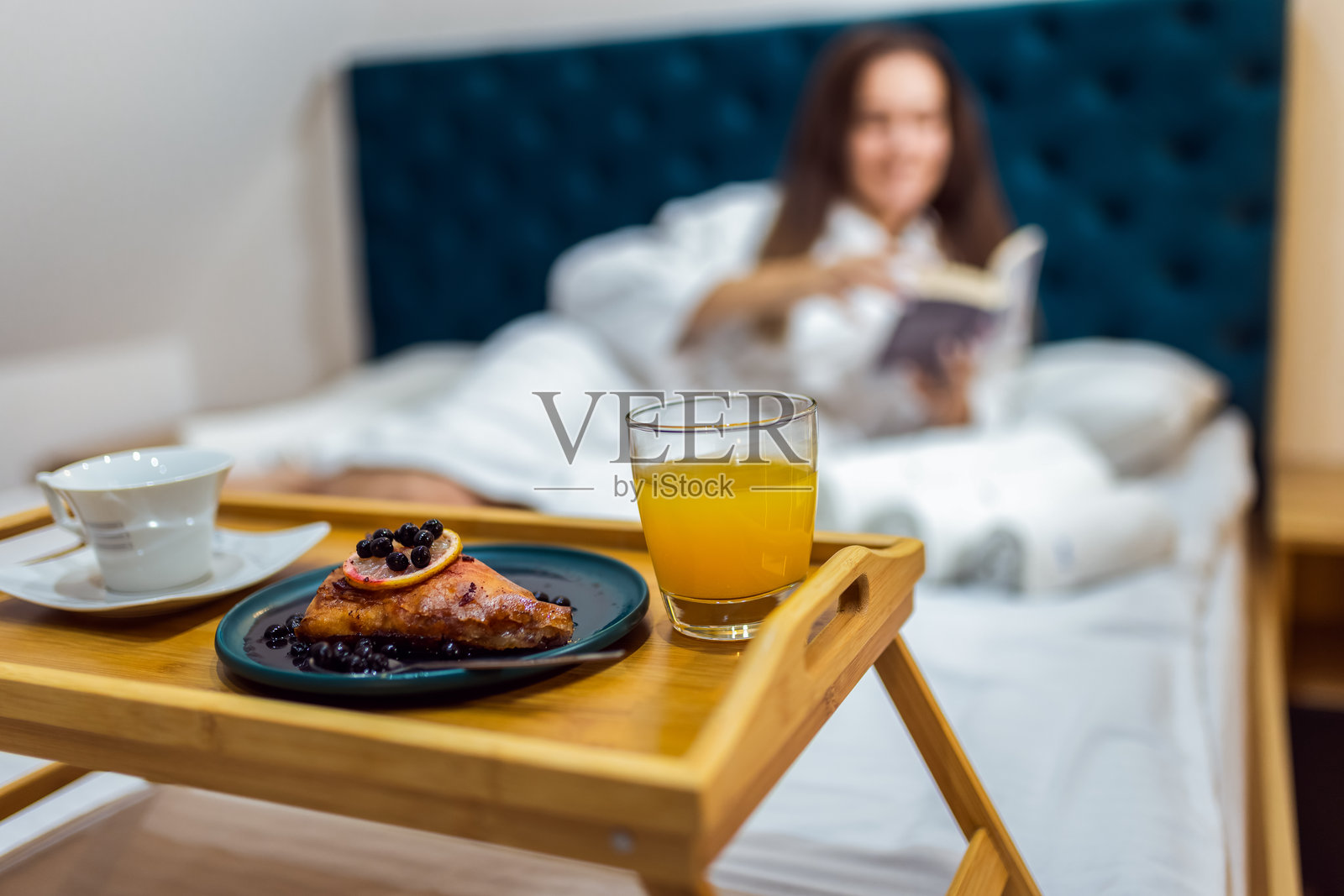 穿着浴袍的漂亮女孩在酒店房间里放松，阅读一本书。照片摄影图片