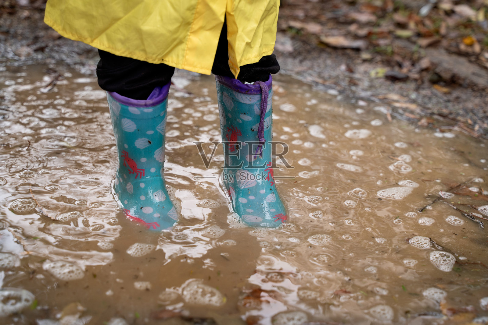 孩子们的雨靴浸泡在水坑中照片摄影图片