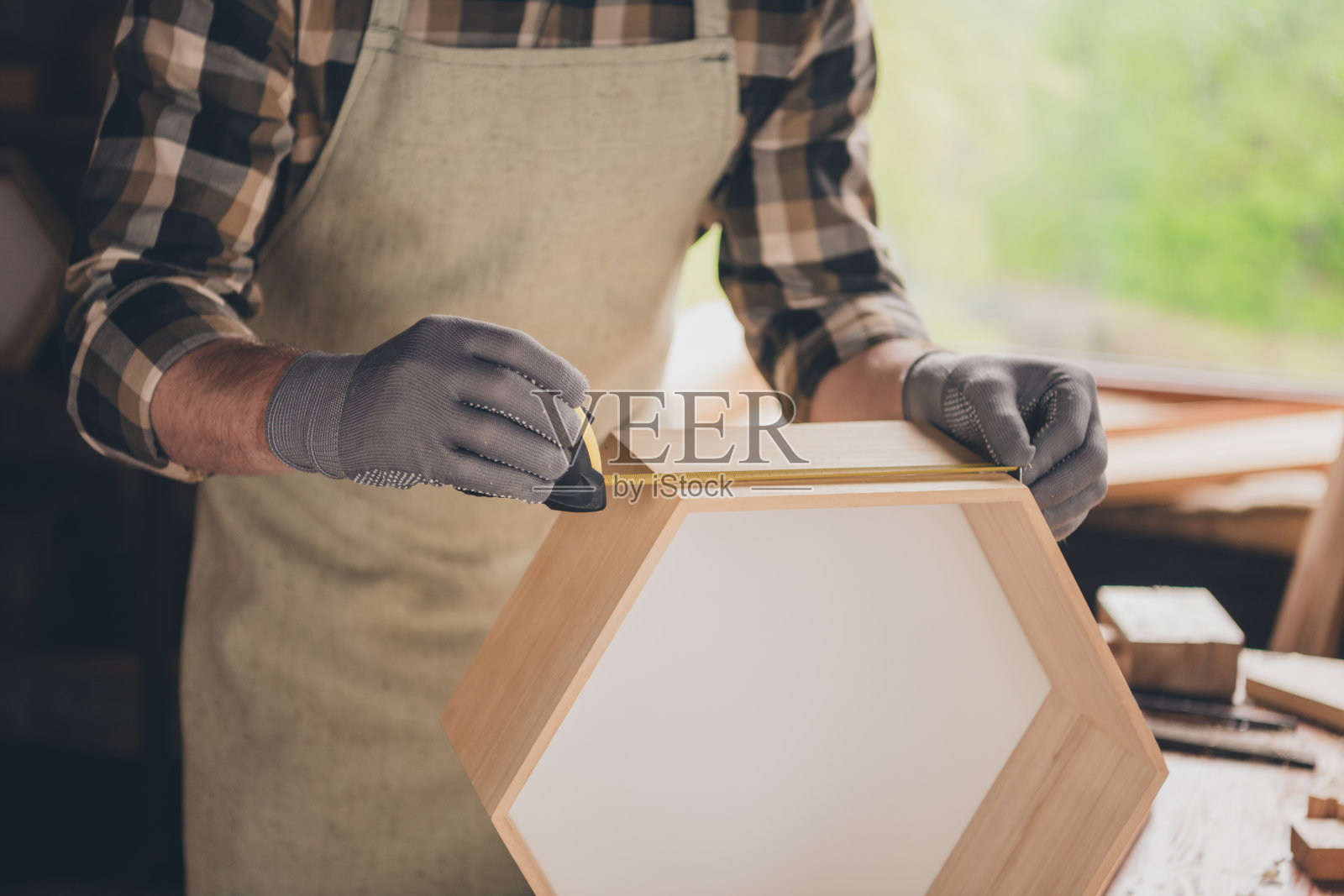 裁剪的照片，木匠在室内车库用卷尺测量木材。照片摄影图片