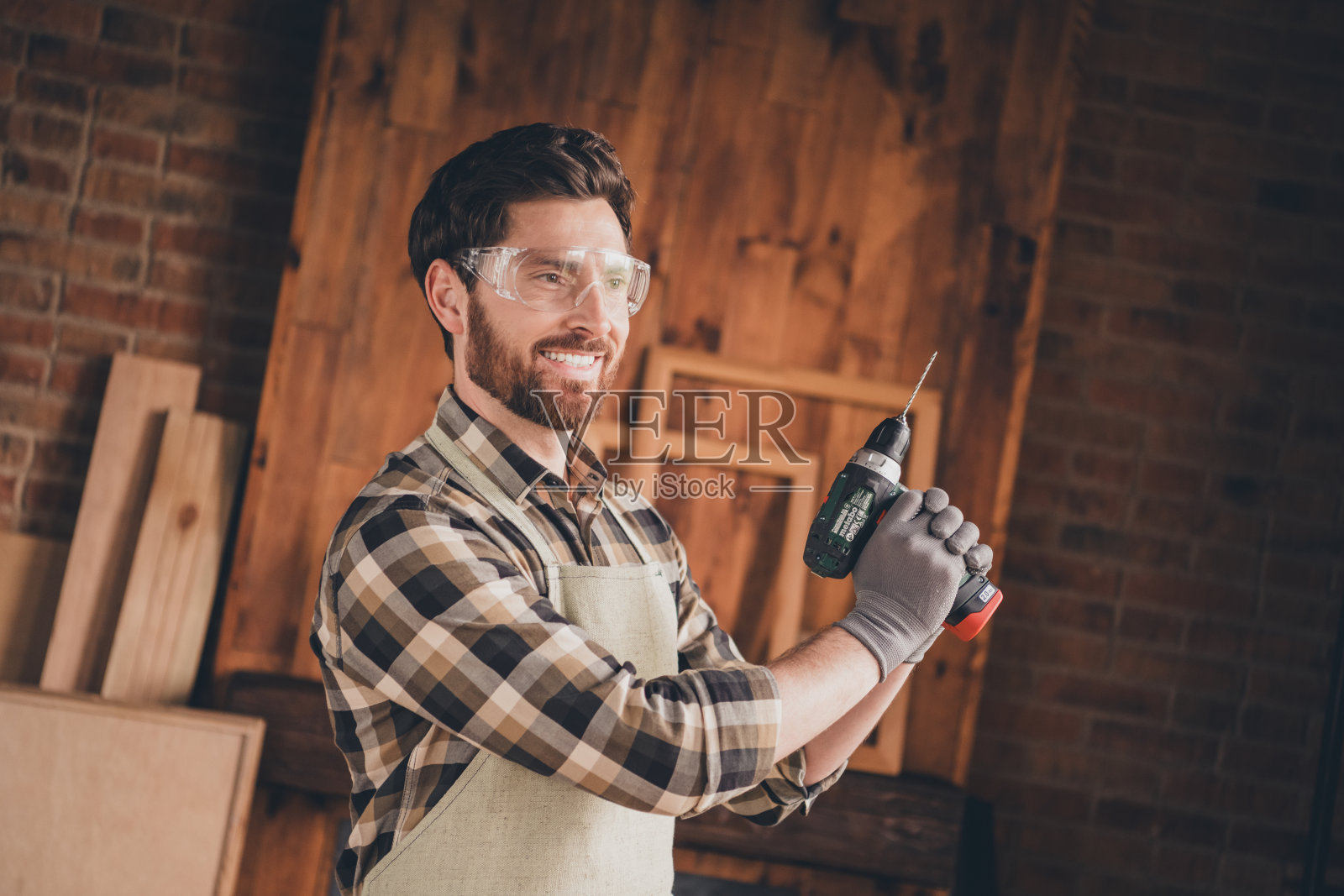 快乐的工人在车库里侧身持电钻工作照片摄影图片