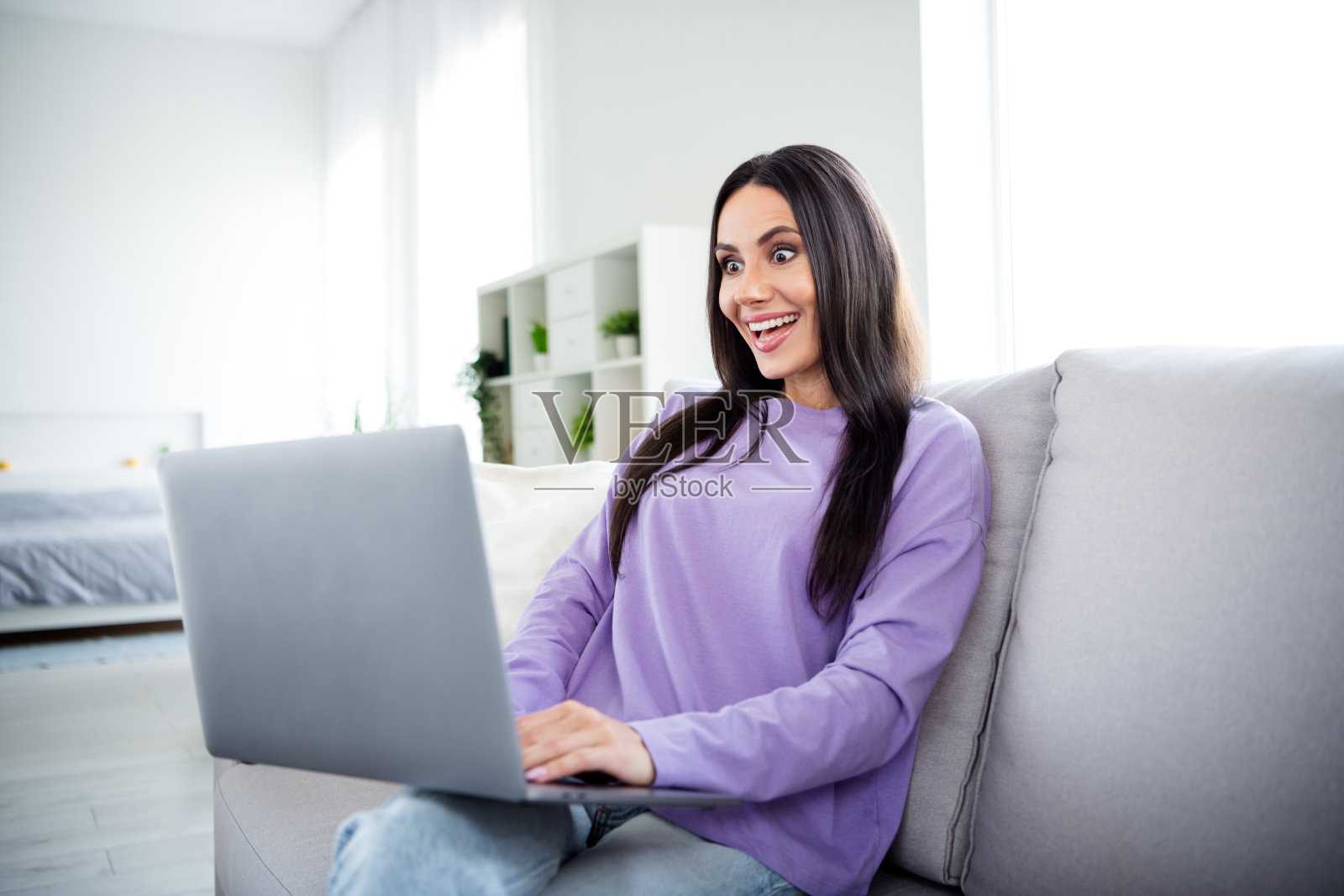 年轻女性在室内沙发上悠闲地使用笔记本电脑照片摄影图片