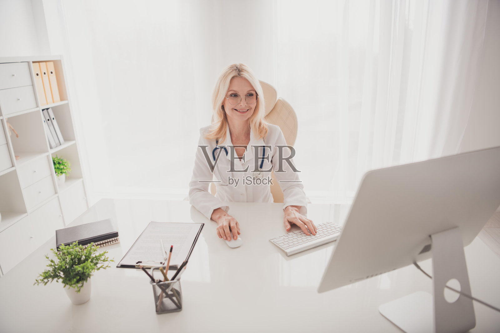 自信的女性高级医生在现代医院办公室使用电脑工作照片摄影图片