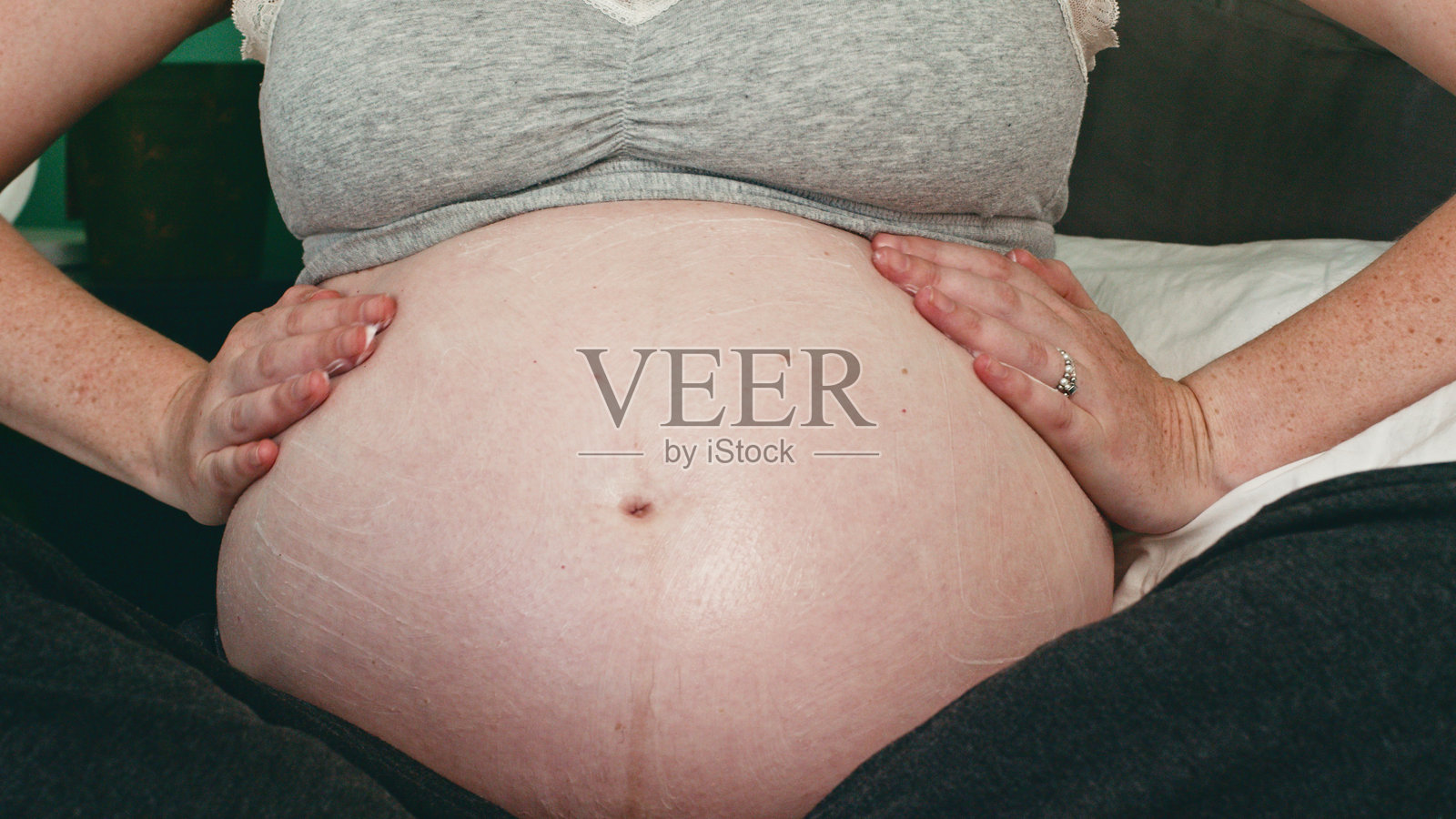 孕妇在舒适的环境中轻柔地用双手托着肚子照片摄影图片