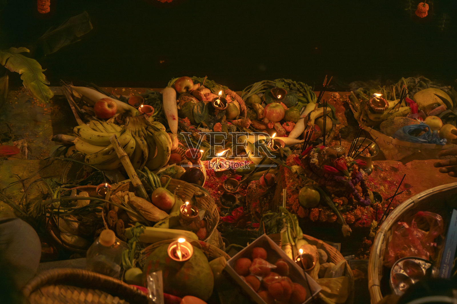 在尼泊尔和印度的河边庆祝查哈节，供奉太阳神，摆放水果、灯光和油灯。照片摄影图片