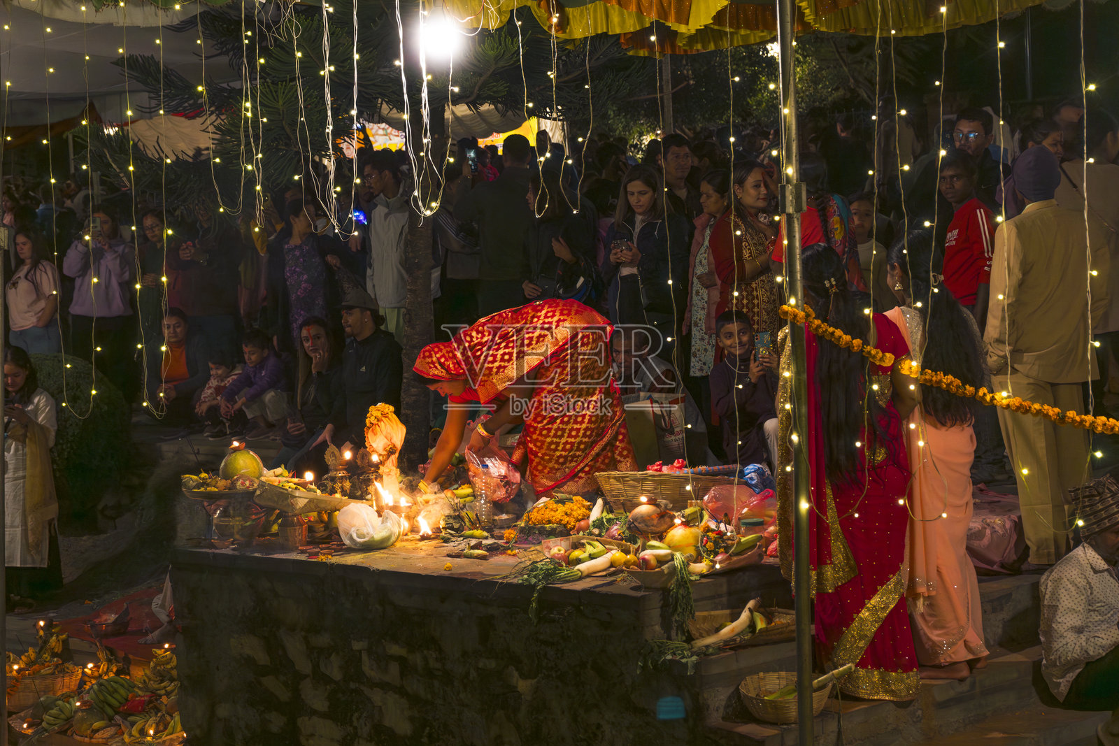在尼泊尔和印度的河边庆祝查哈节，供奉太阳神，摆放水果、灯光和油灯。照片摄影图片