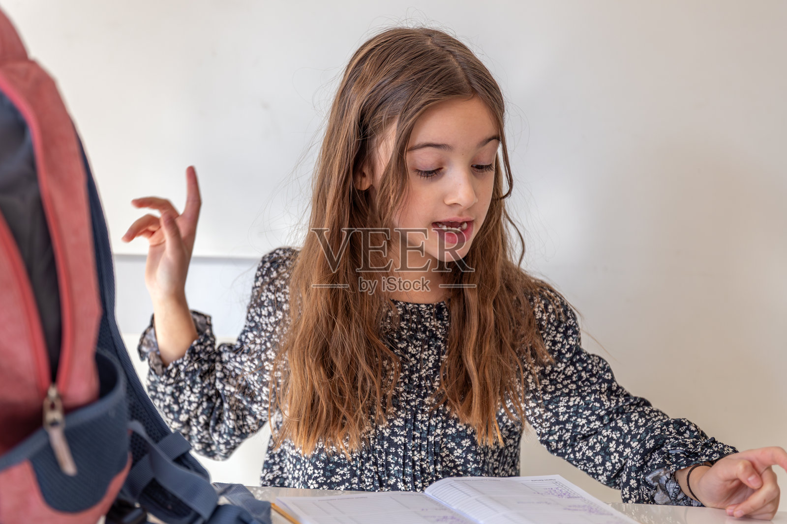 快乐的女孩在家里阅读一本书。女孩正在为学校的课程做准备。照片摄影图片