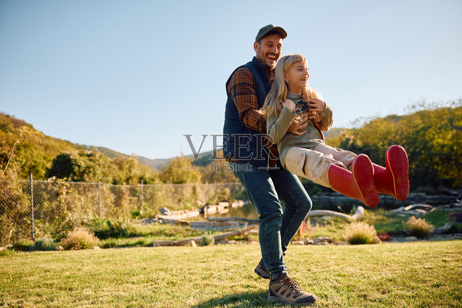 在大自然中旋转女儿的顽皮父亲。照片摄影图片