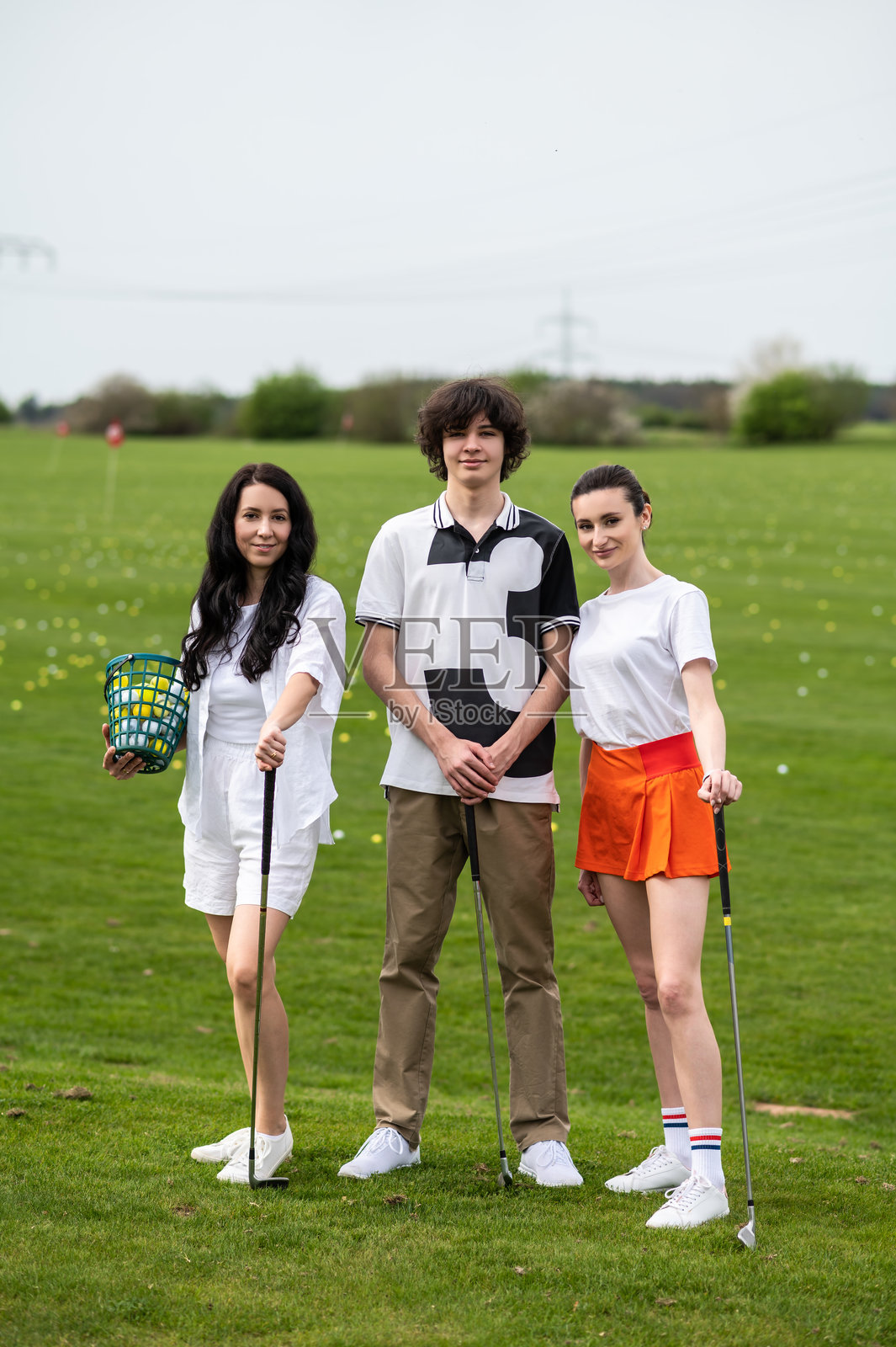 年轻高尔夫球手手持铁杆站在高尔夫球场上照片摄影图片