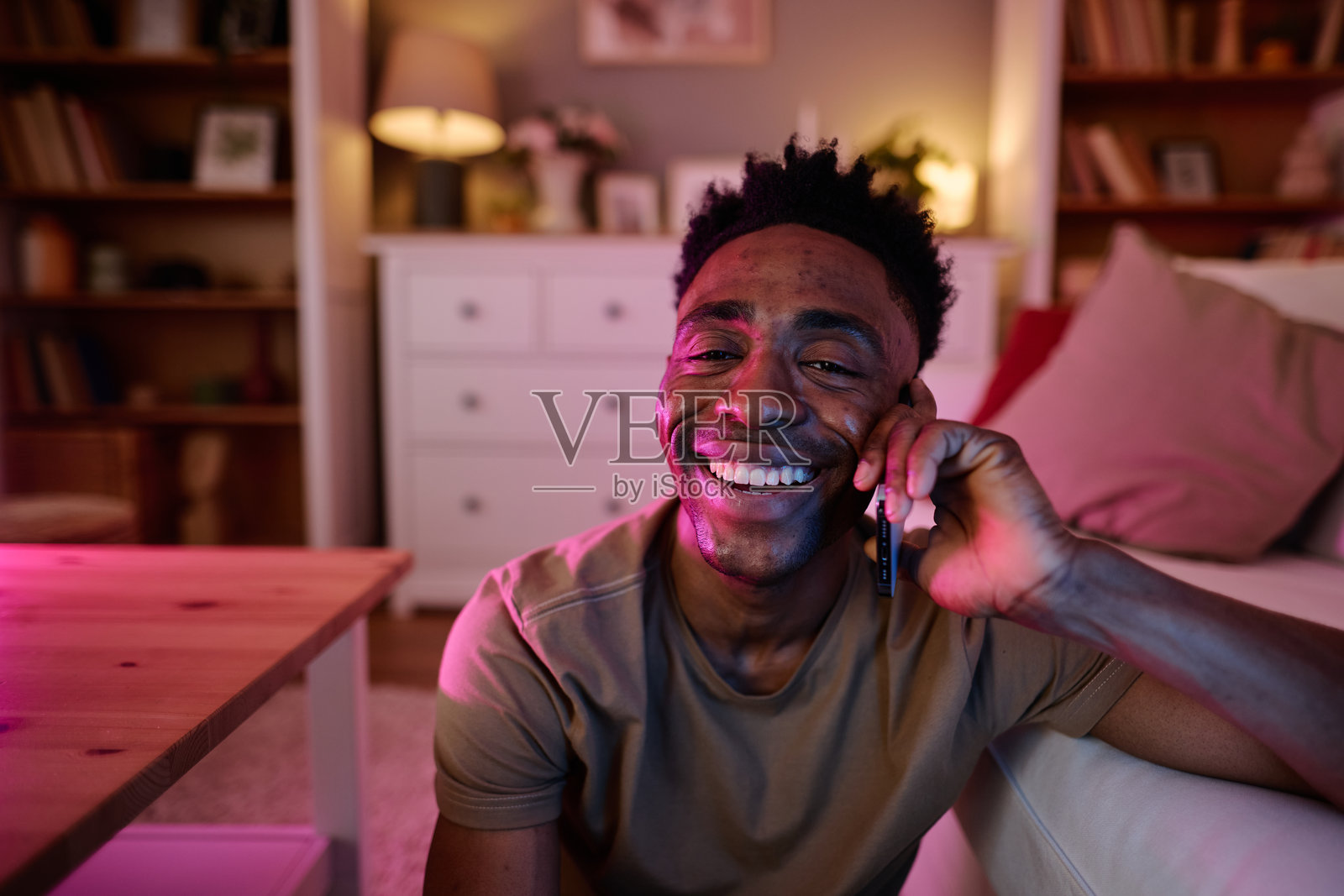 快乐的男人在客厅里打电话时大笑照片摄影图片