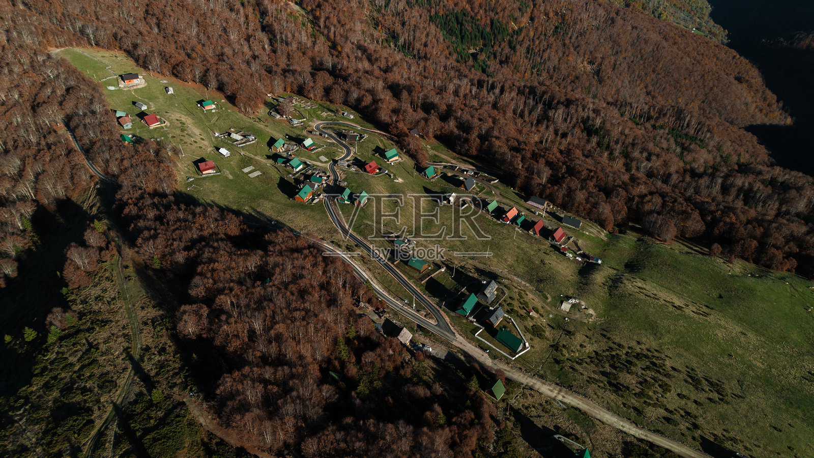 黑山科莫维山谷秋季的村庄航拍图。美丽壮观的山地风景。小房子有着五彩斑斓的屋顶，周围是金色的森林。照片摄影图片