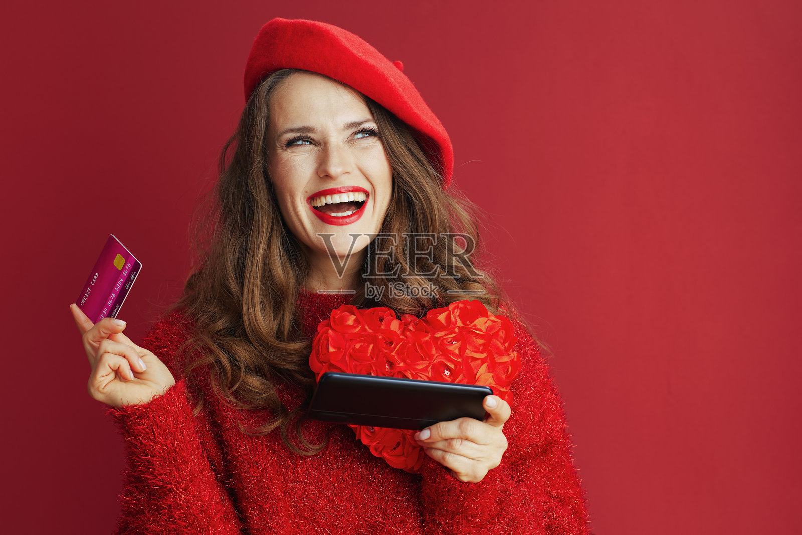 穿着红色毛衣和贝雷帽的时尚快乐女性在网上购物照片摄影图片