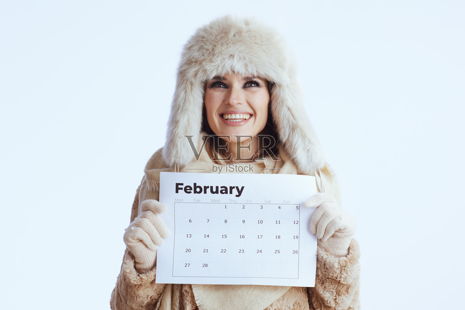 穿着冬季外套和毛皮帽子的时尚快乐女性在白色背景上照片摄影图片