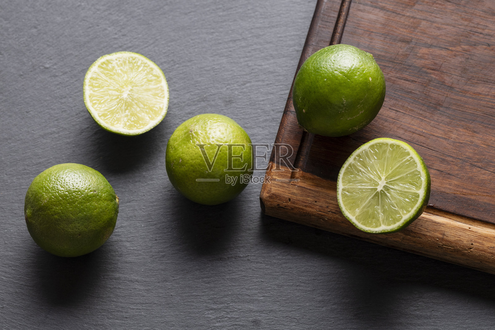 新鲜的绿色青柠在黑色石板背景上照片摄影图片