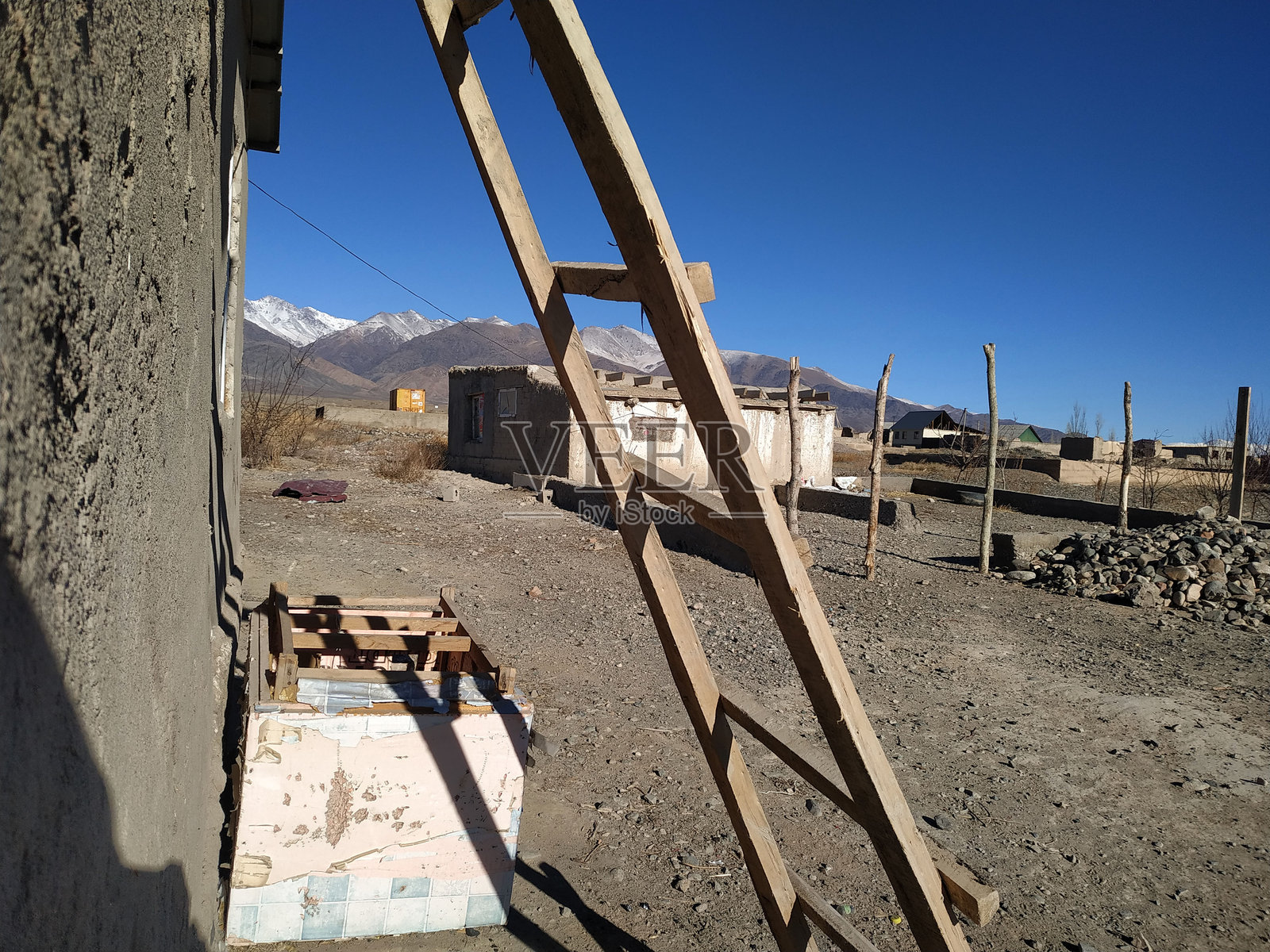 一架木梯靠在一座乡村建筑上，背景是晴朗的蓝天，位于偏远的山区，白天时分。照片摄影图片