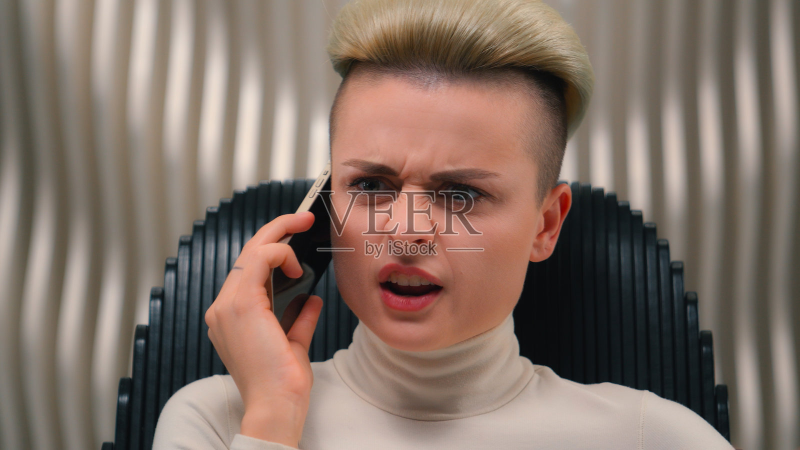 愤怒的白人女性商人，在未来派工作室的元宇宙中，因与手机通话而大声喊叫，表现出愤怒和负面情绪。照片摄影图片