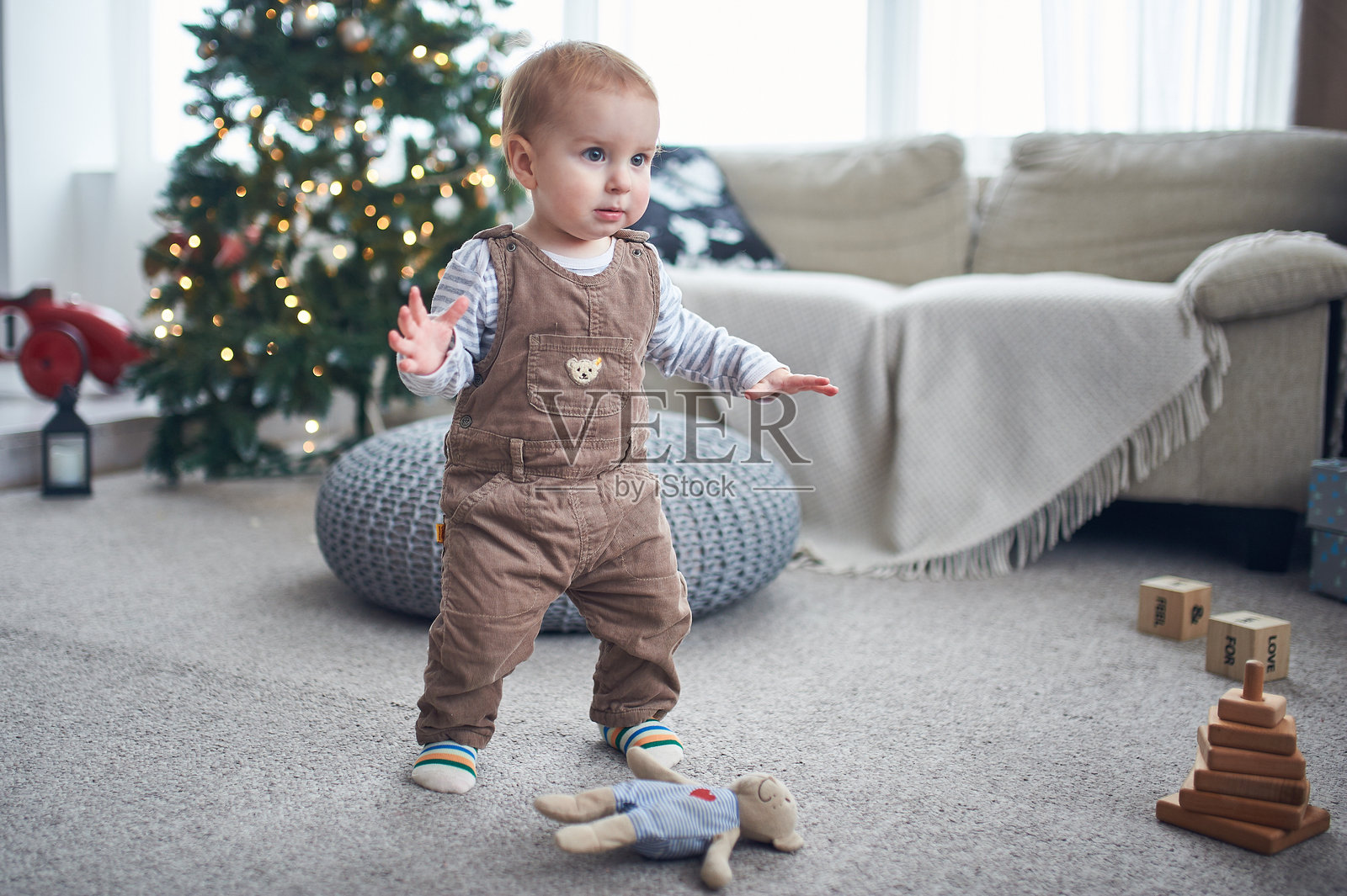 孩子在节日期间探索温馨的客厅，背景中有一棵圣诞树照片摄影图片