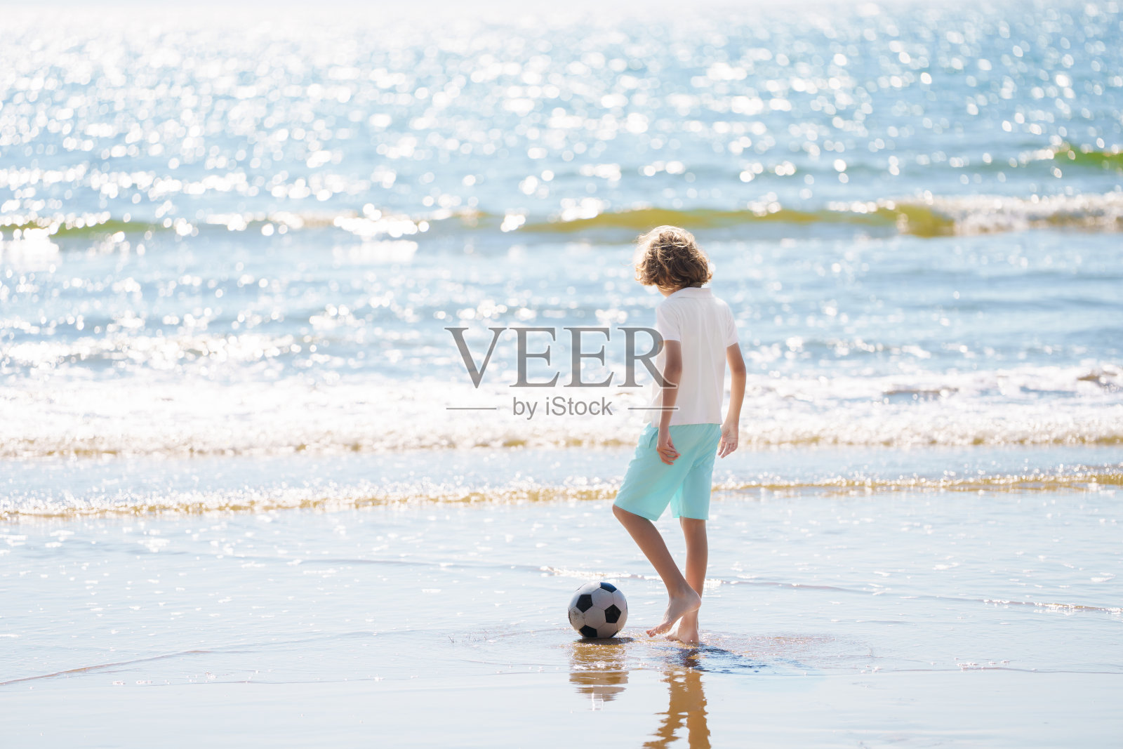 祖父和孩子们在海滩上踢足球。照片摄影图片