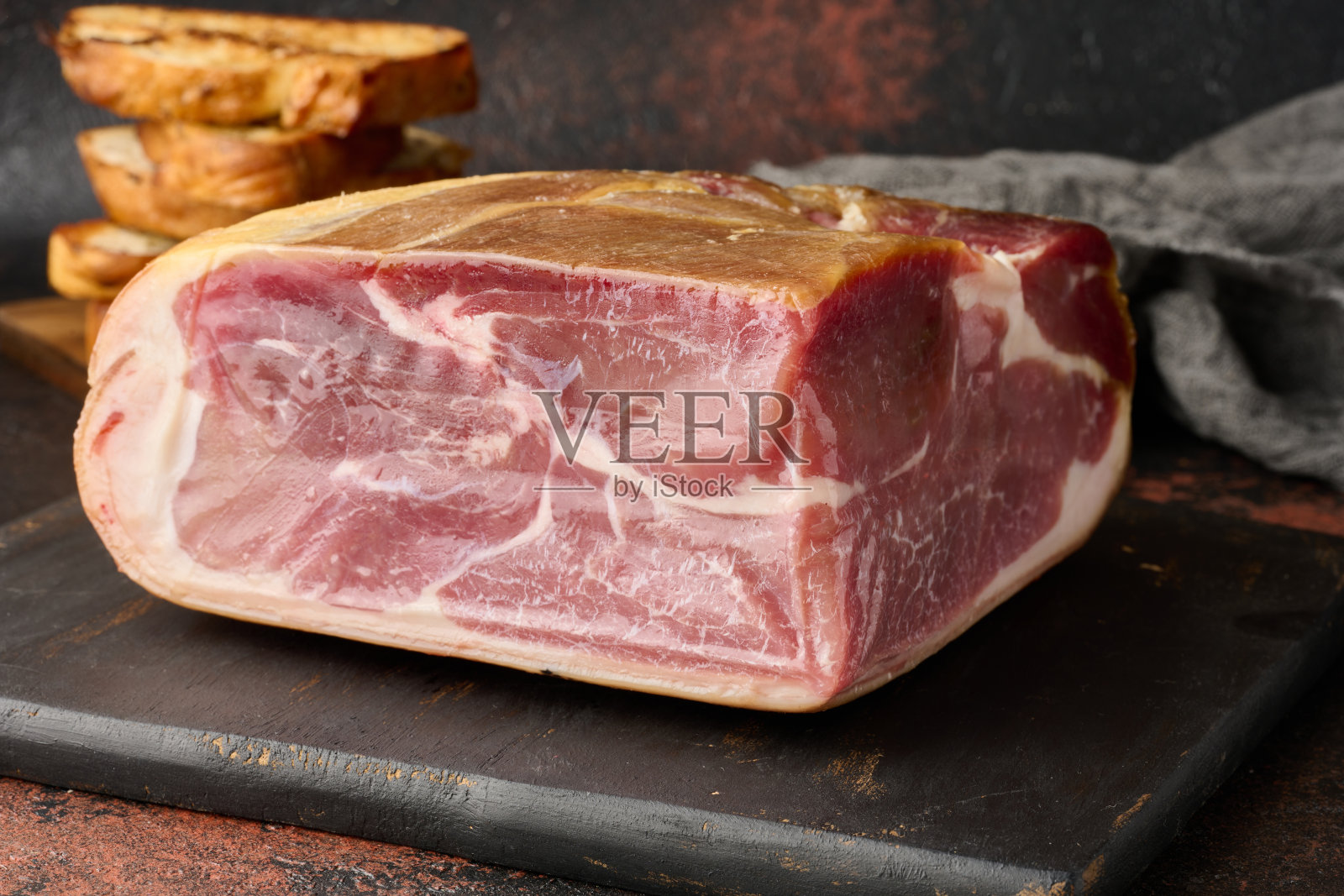 一块火腿，几片恰巴塔面包放在木板上照片摄影图片