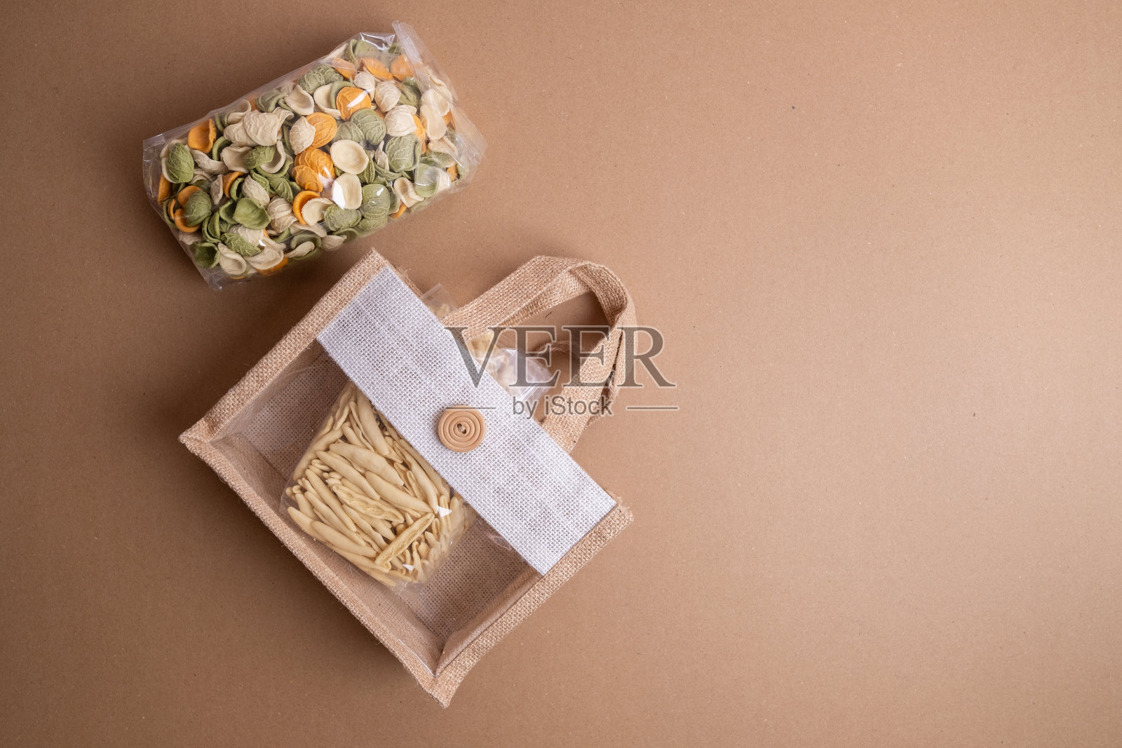 透明塑料袋装的意大利面。生意大利面的特写背景。各种类型的意大利面和面条在彩色背景上。意大利美食烹饪概念。不同生意大利面的集合。照片摄影图片