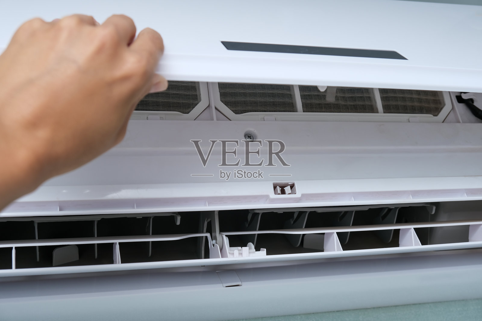 一个人打开空调以进行维护和清洁灰尘。照片摄影图片