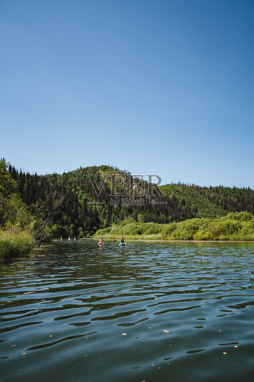 一个人在宁静的湖面上划船，周围是雄伟的山脉，形成了一个令人叹为观止的自然风光，水、天空、湖泊和山脉是关键元素。照片摄影图片