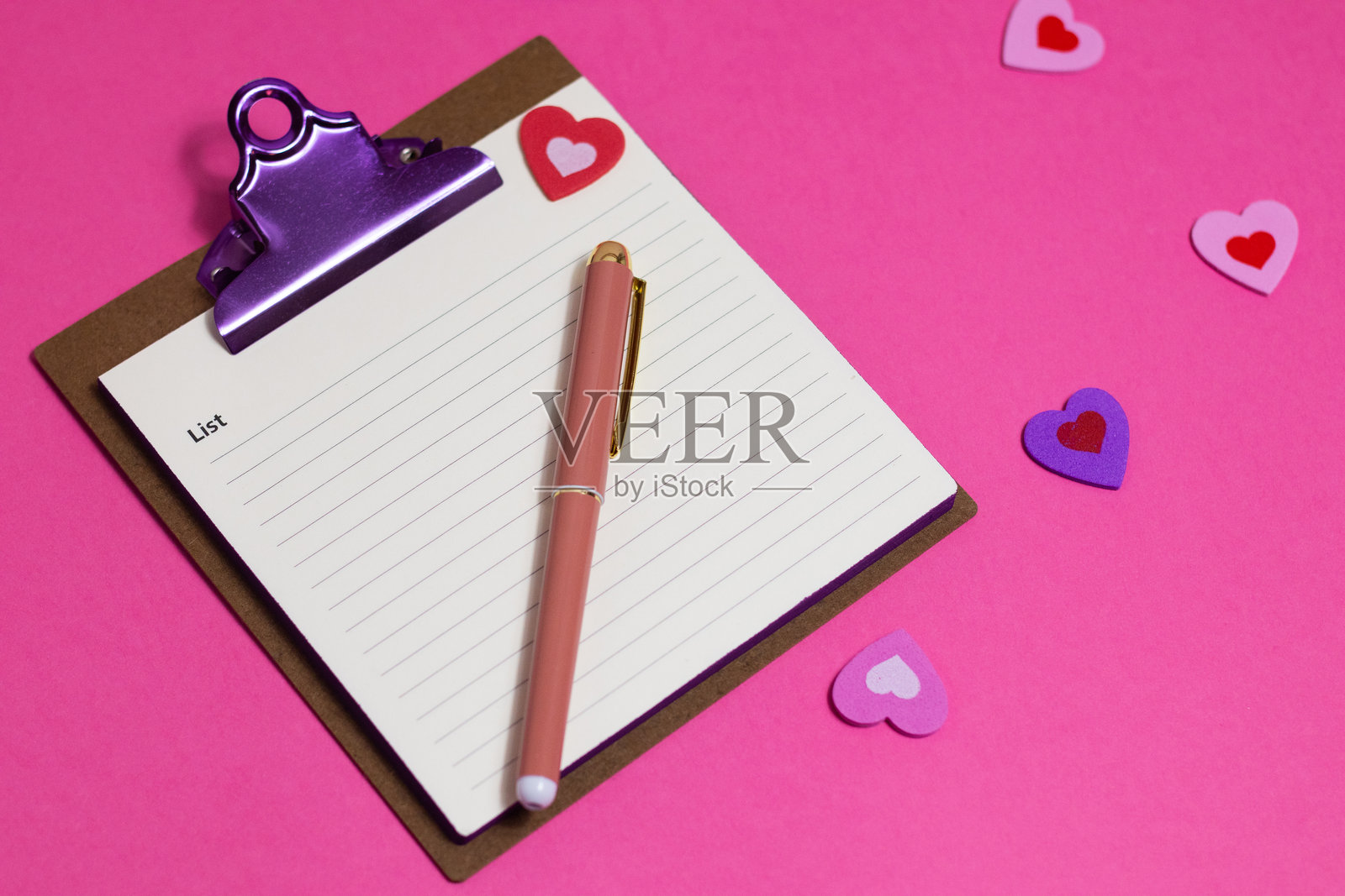女性粉色办公桌。粉色背景上的记事本、钢笔和贴纸。平铺视角，俯视图，留白，横幅。照片摄影图片