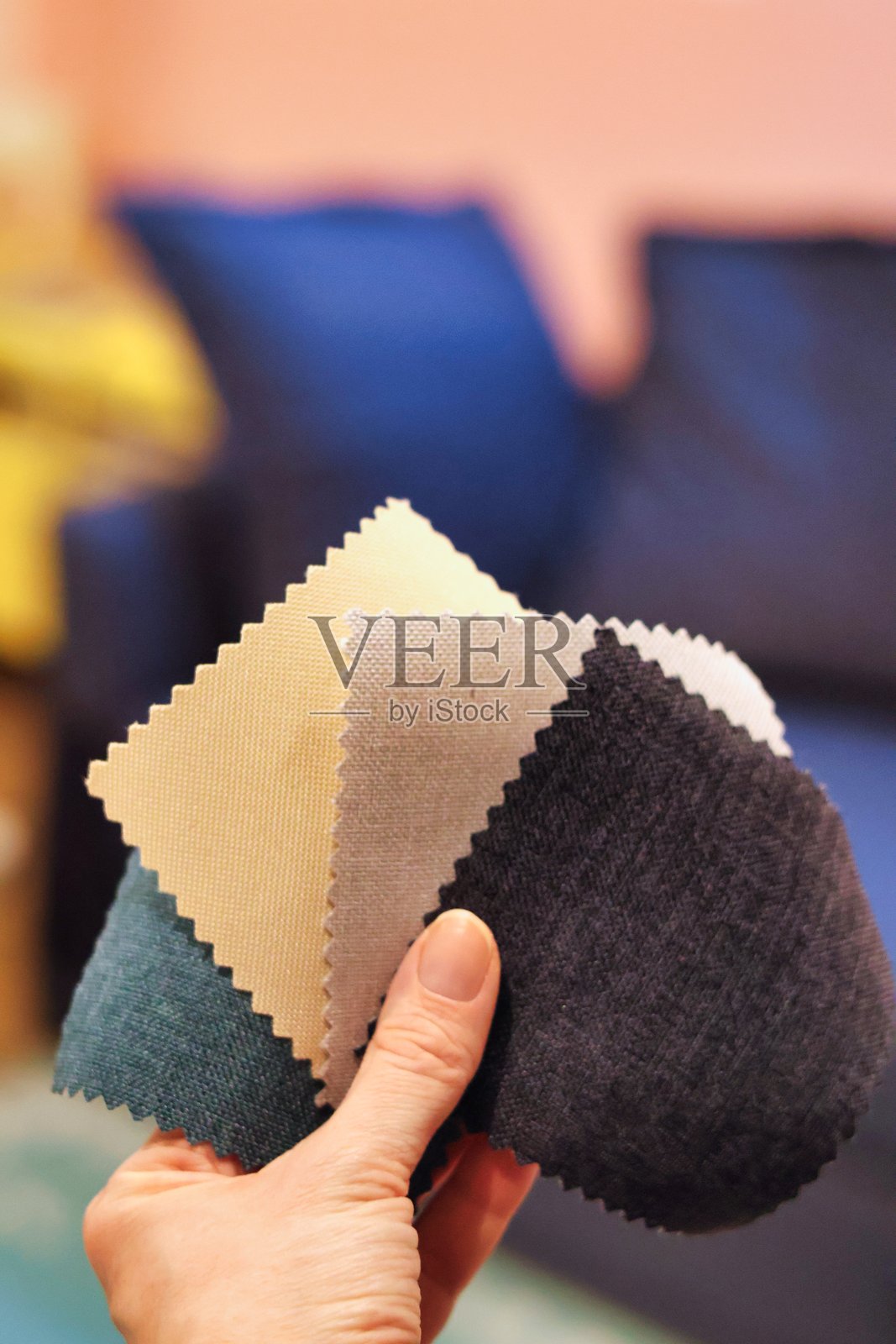 手拿材料样本，背景是一张沙发照片摄影图片