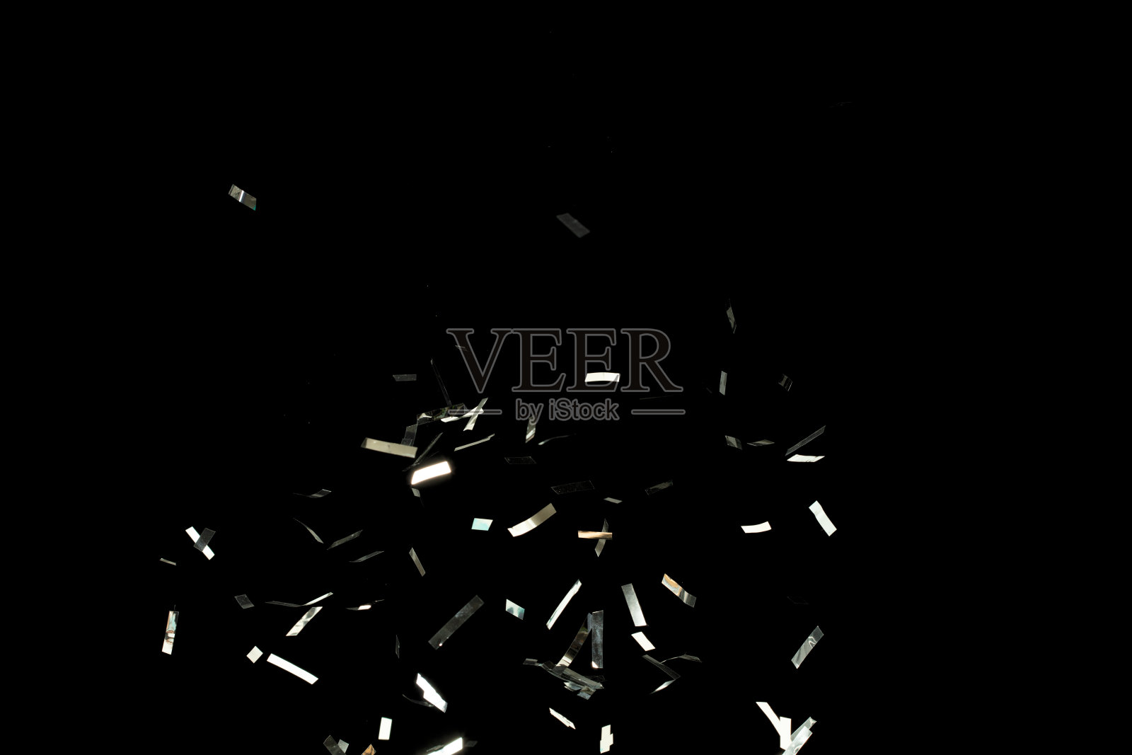 许多派对闪光片散落在多个组中。银色纸屑在空中飞舞。银色纸屑爆炸飞扬，形成抽象的云彩。黑色背景下的孤立元素冻结。照片摄影图片