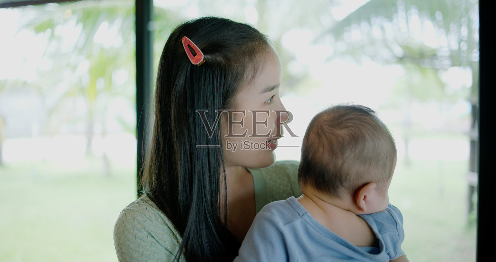 一位年轻女性在温馨的咖啡店里抱着一个婴儿。照片摄影图片