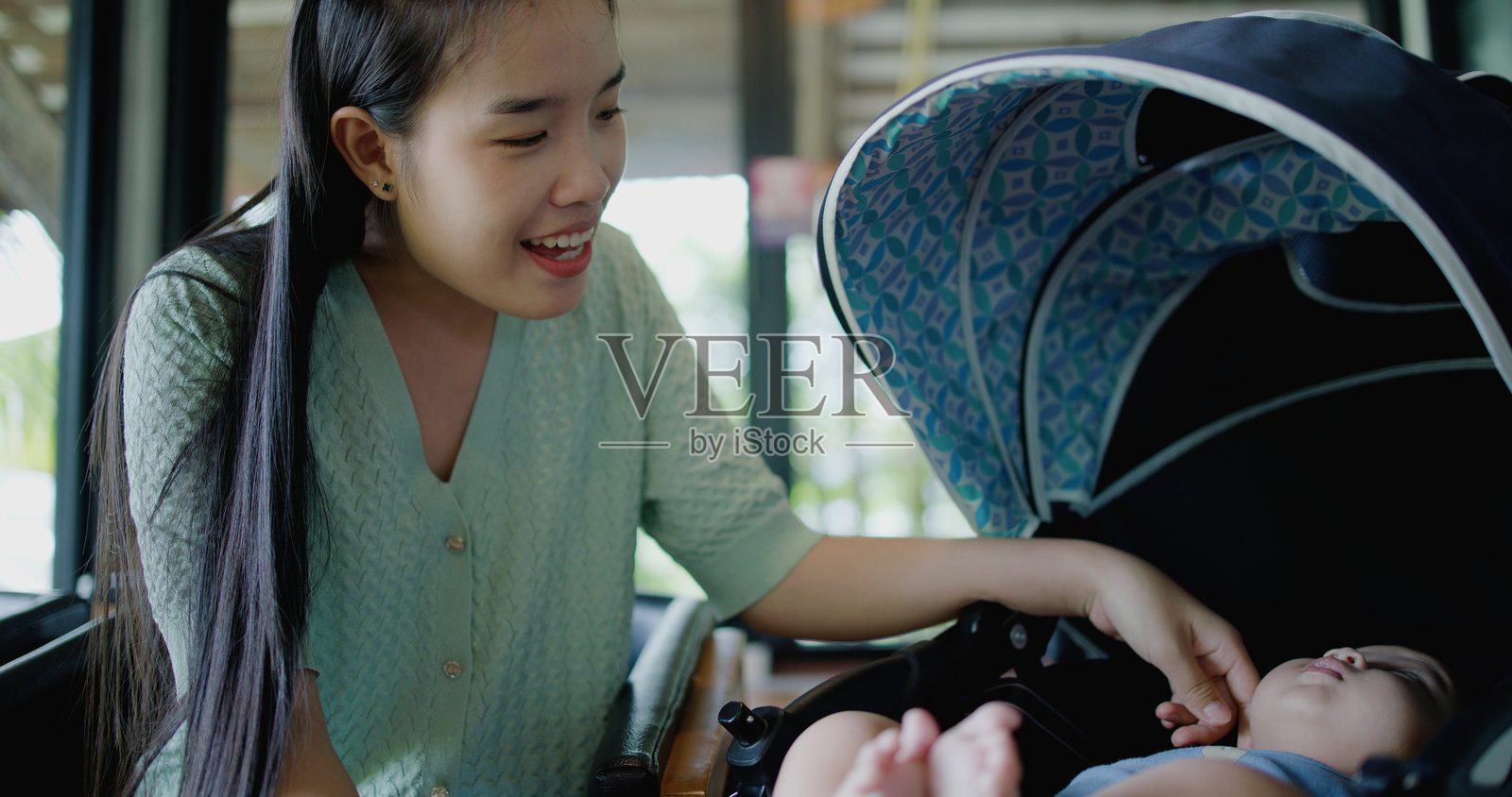 年轻女性在咖啡馆与小男孩玩耍。照片摄影图片