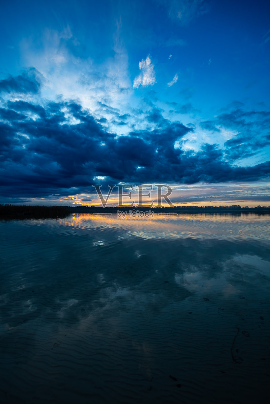 宁静的日落优雅地映照在平静的水面上，反射出美丽的云彩。照片摄影图片