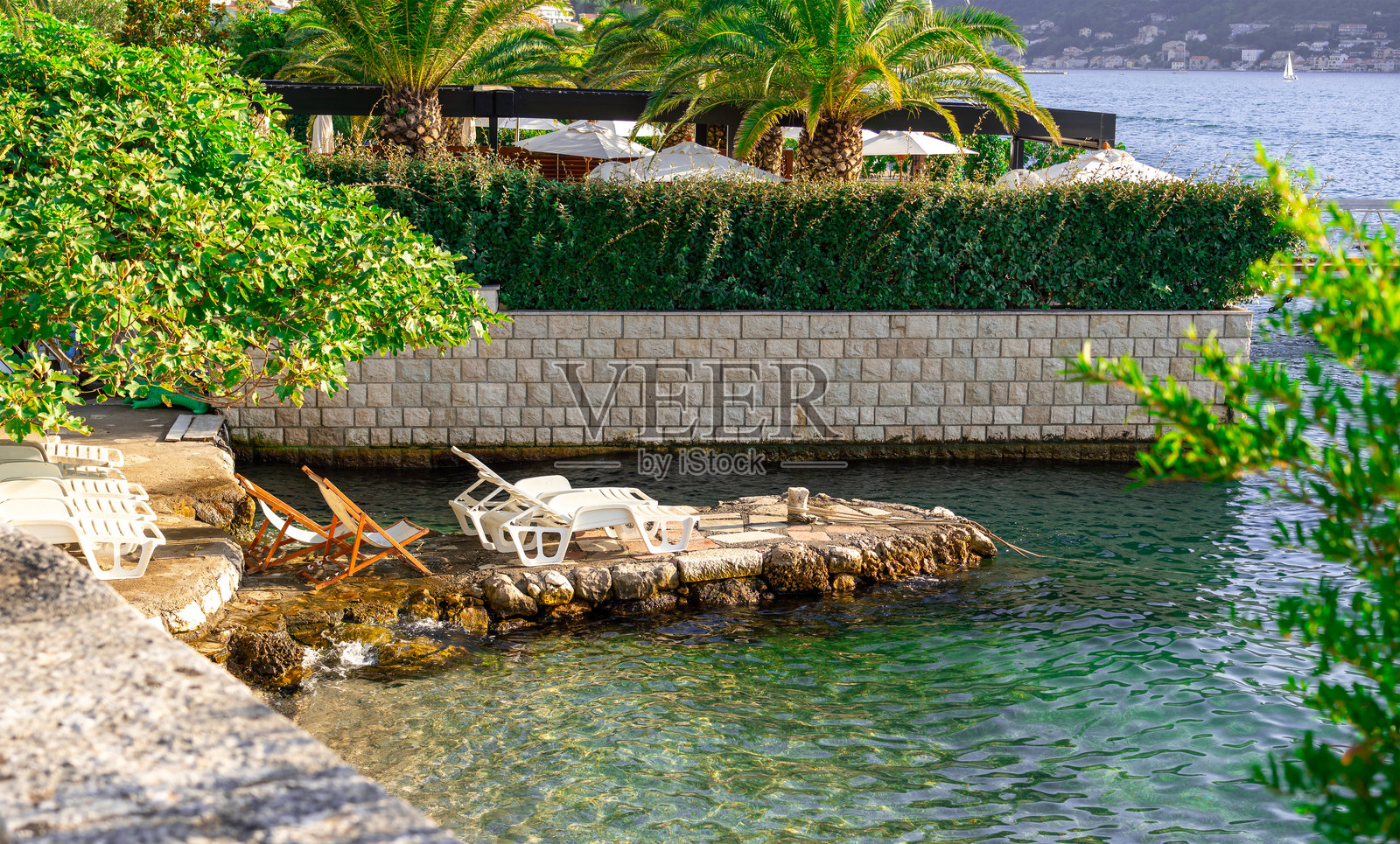 宁静的水边景点，岸边有舒适的躺椅和郁郁葱葱的绿植照片摄影图片