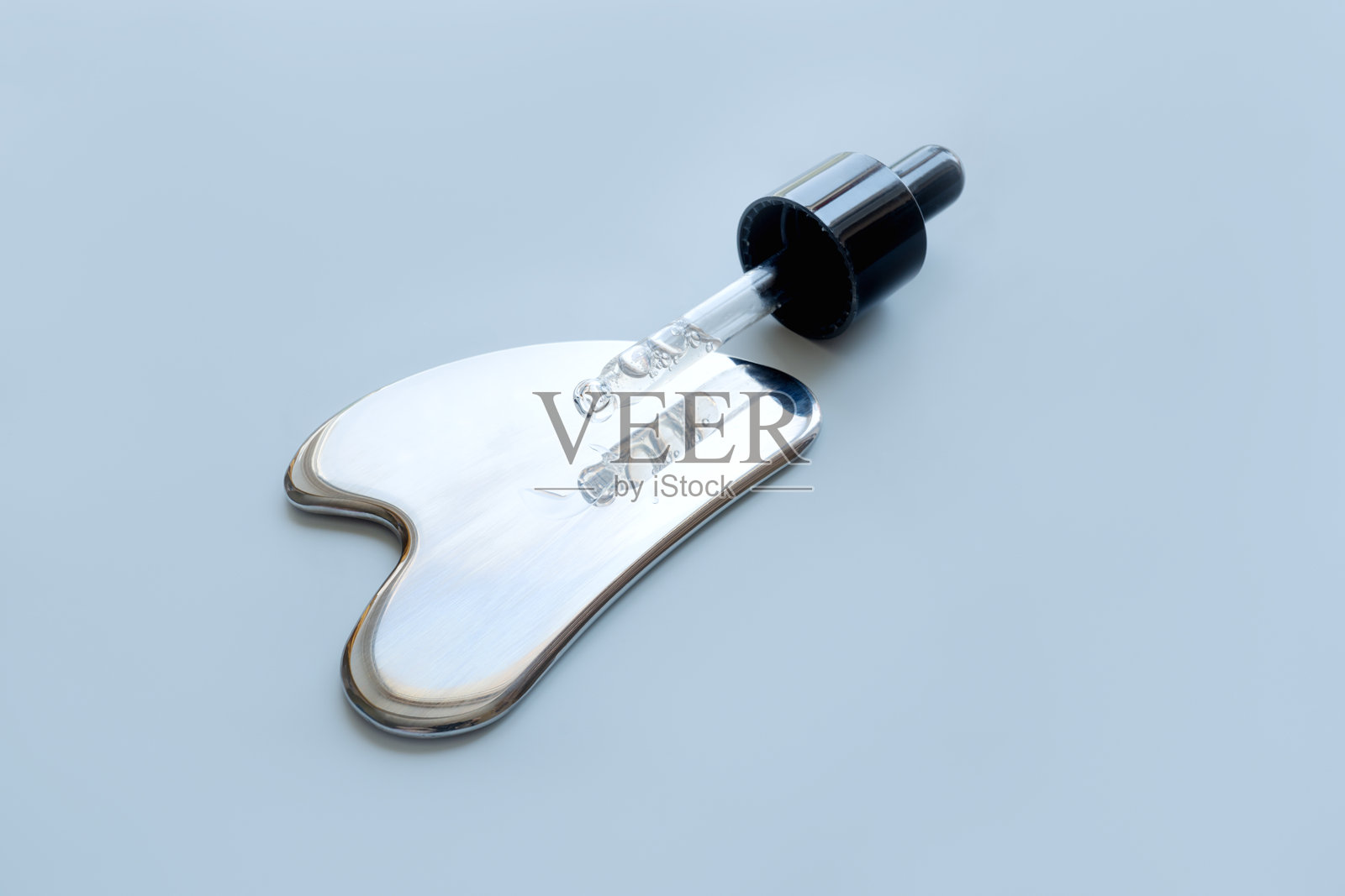 不锈钢刮痧工具和一支装有化妆品的滴管照片摄影图片
