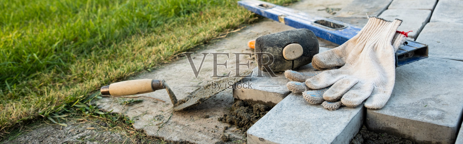 在水泥砂浆上铺设铺路石。铺设由瓷砖制成的花园小径。在房屋院子里自助铺设混凝土铺路砖。自己动手。DIY照片摄影图片