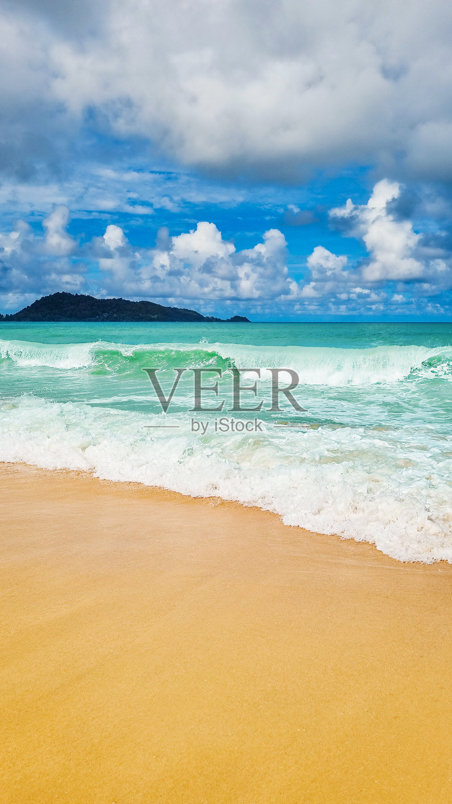 热带海岸线，阳光明媚的黄色沙滩，蓝色海洋波涛汹涌，天空中飘着白云。照片摄影图片