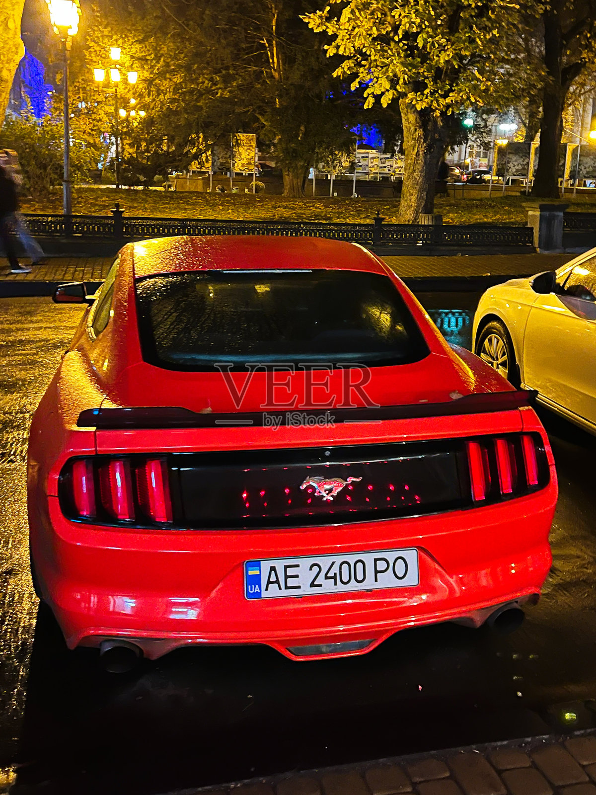 红色运动福特野马汽车停在城市街道上,夜晚时分。照片摄影图片