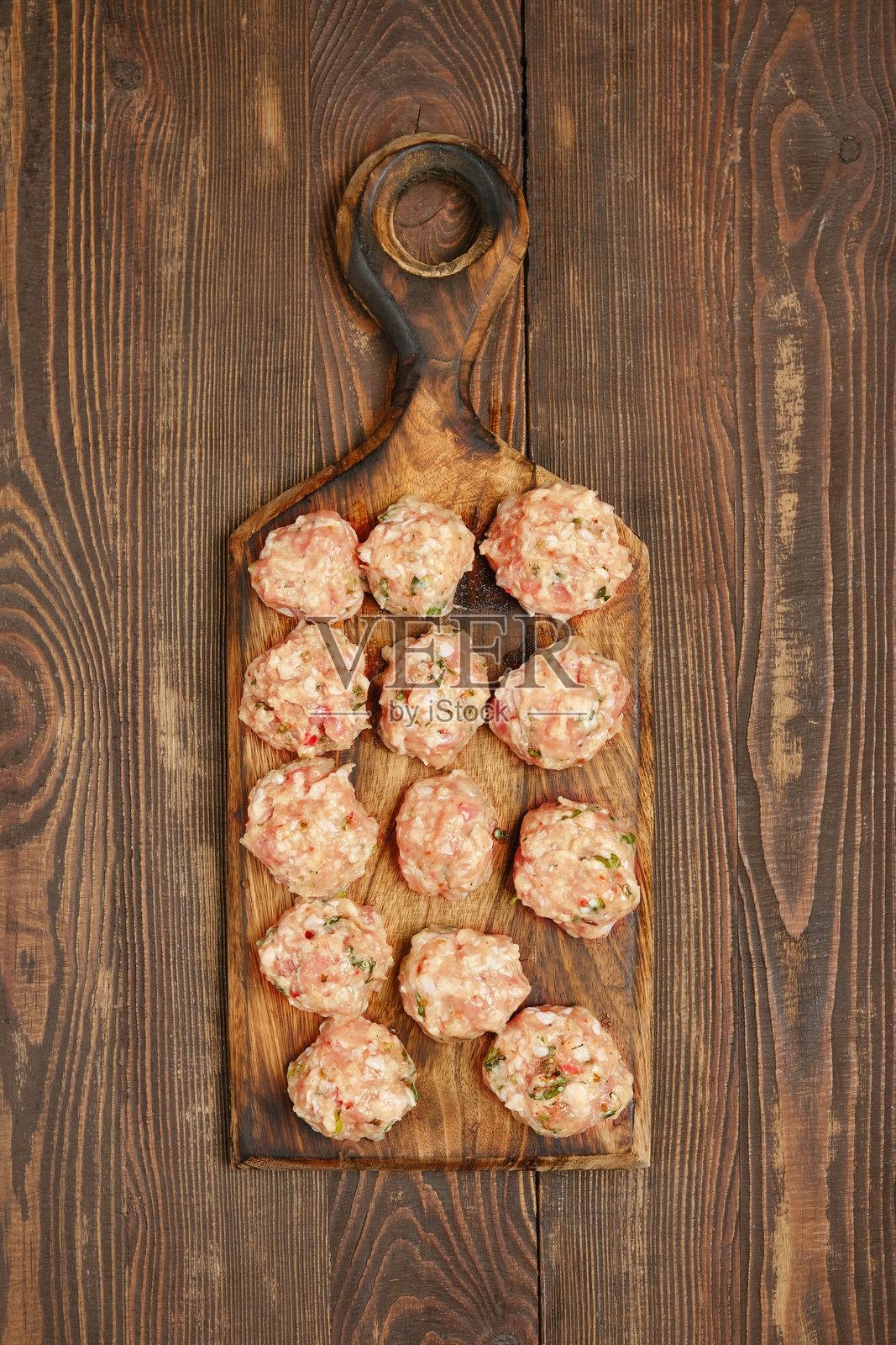 新鲜准备好的肉丸放在木砧板上，准备在温馨的厨房中烹饪照片摄影图片