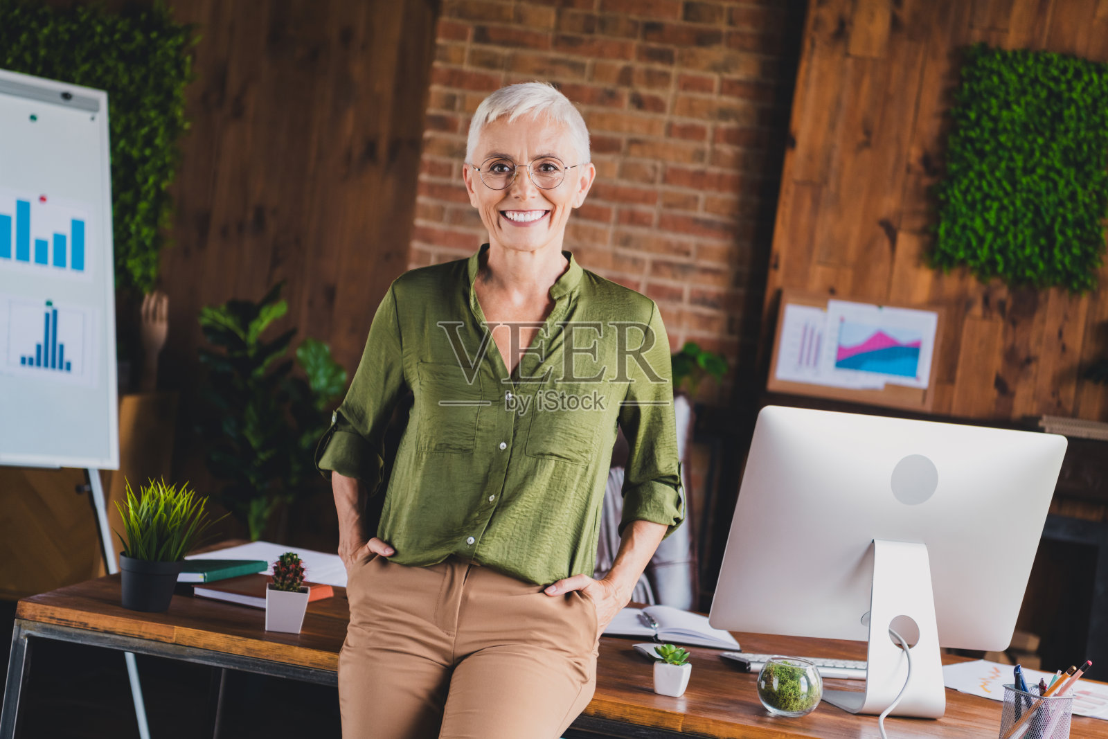迷人的女老板穿着衬衫，戴着眼镜，坐在工作场所的阁楼室内。照片摄影图片